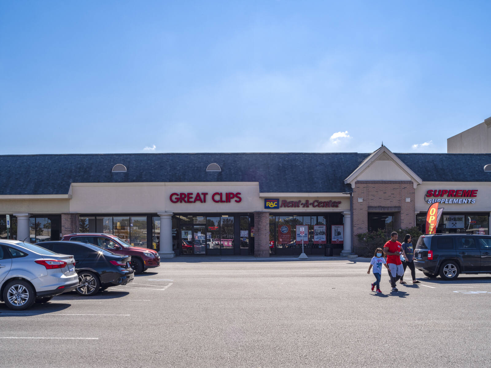 Family exiting Great Clips into the parking lot.
