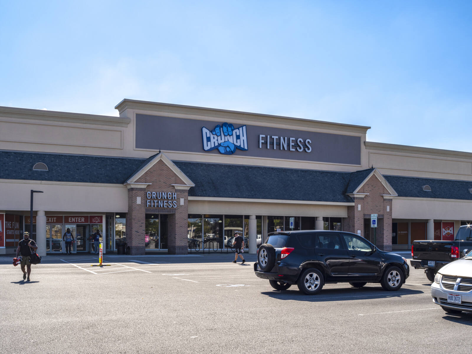 Patrons enter and exit busy Crunch Fitness via the parking lot.