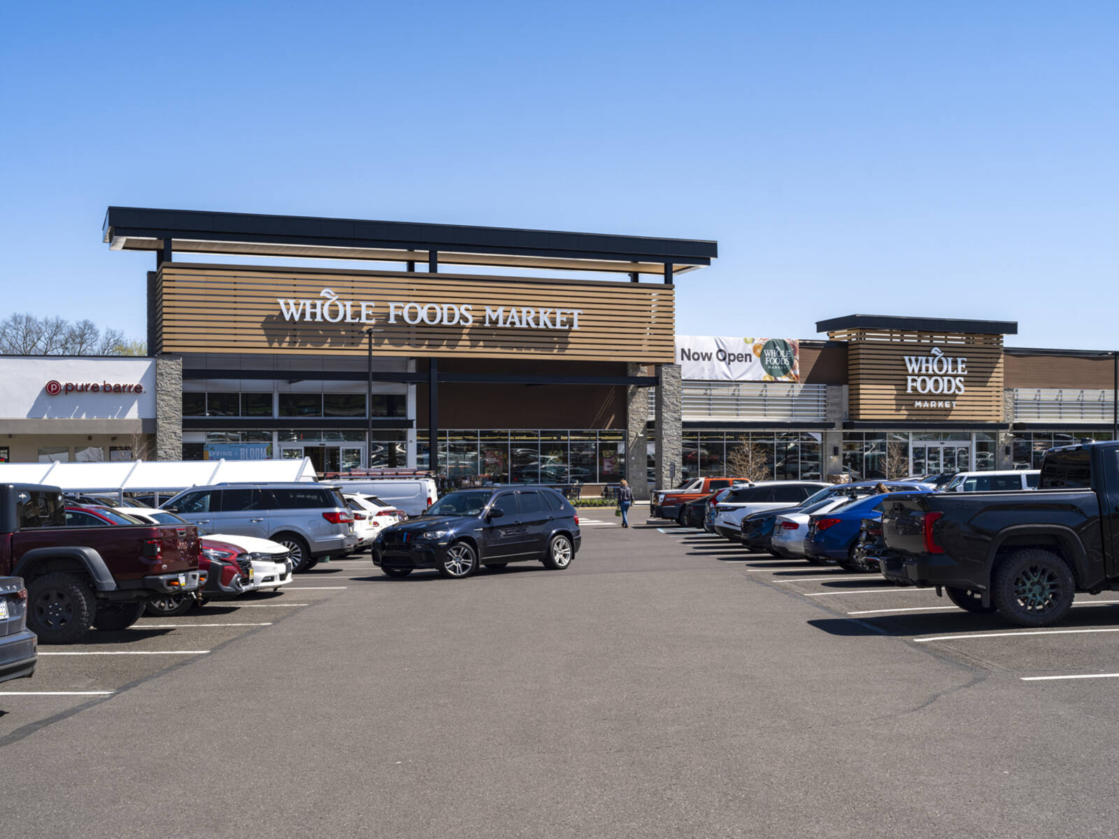Busy parking lot in front of Whole Foods Market with clear blue sky in back.