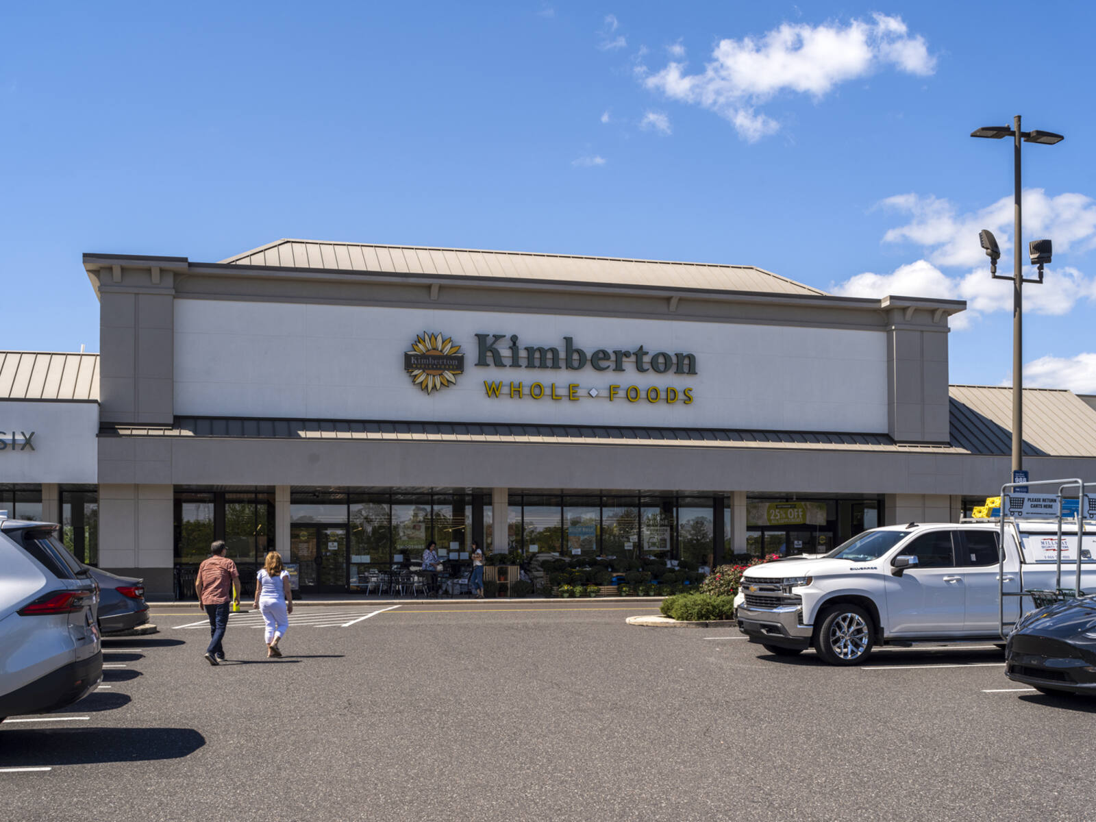 Two patrons approach Kimberton Whole Foods through parking lot.