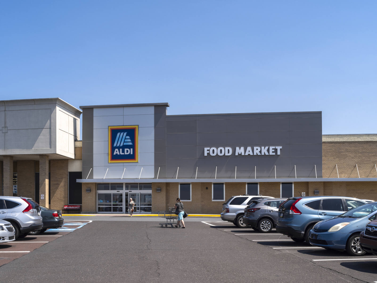 Aldi parking lot with patrons pushing cars in parking lot.