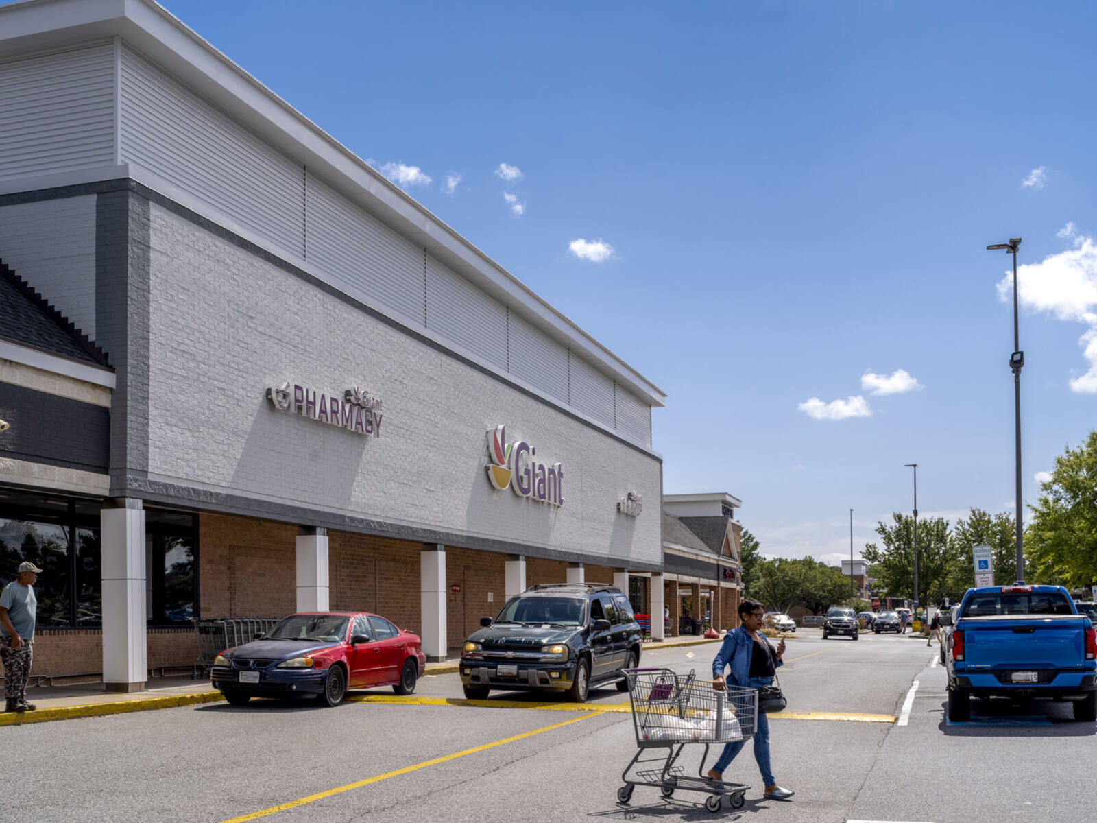 Woman crossing road with a carriage in front of Giant grocery store.