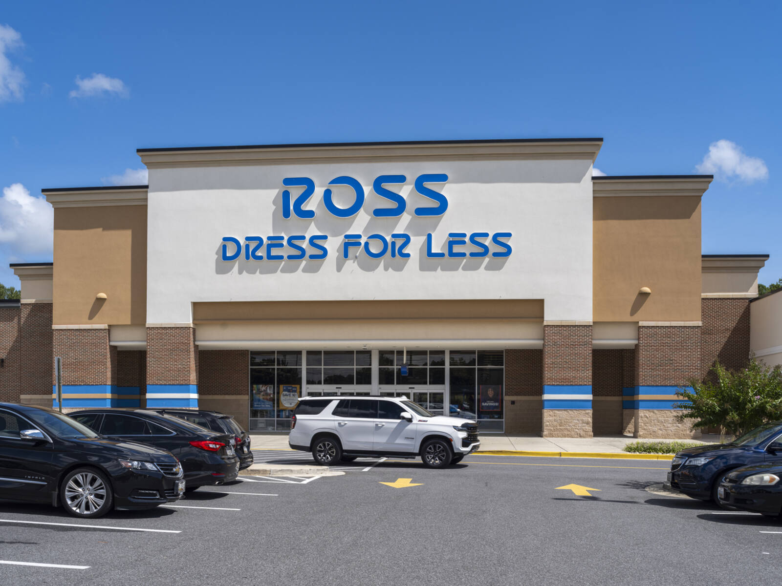 White Jeep passing storefront of Ross Dess for Less in the parking lot.