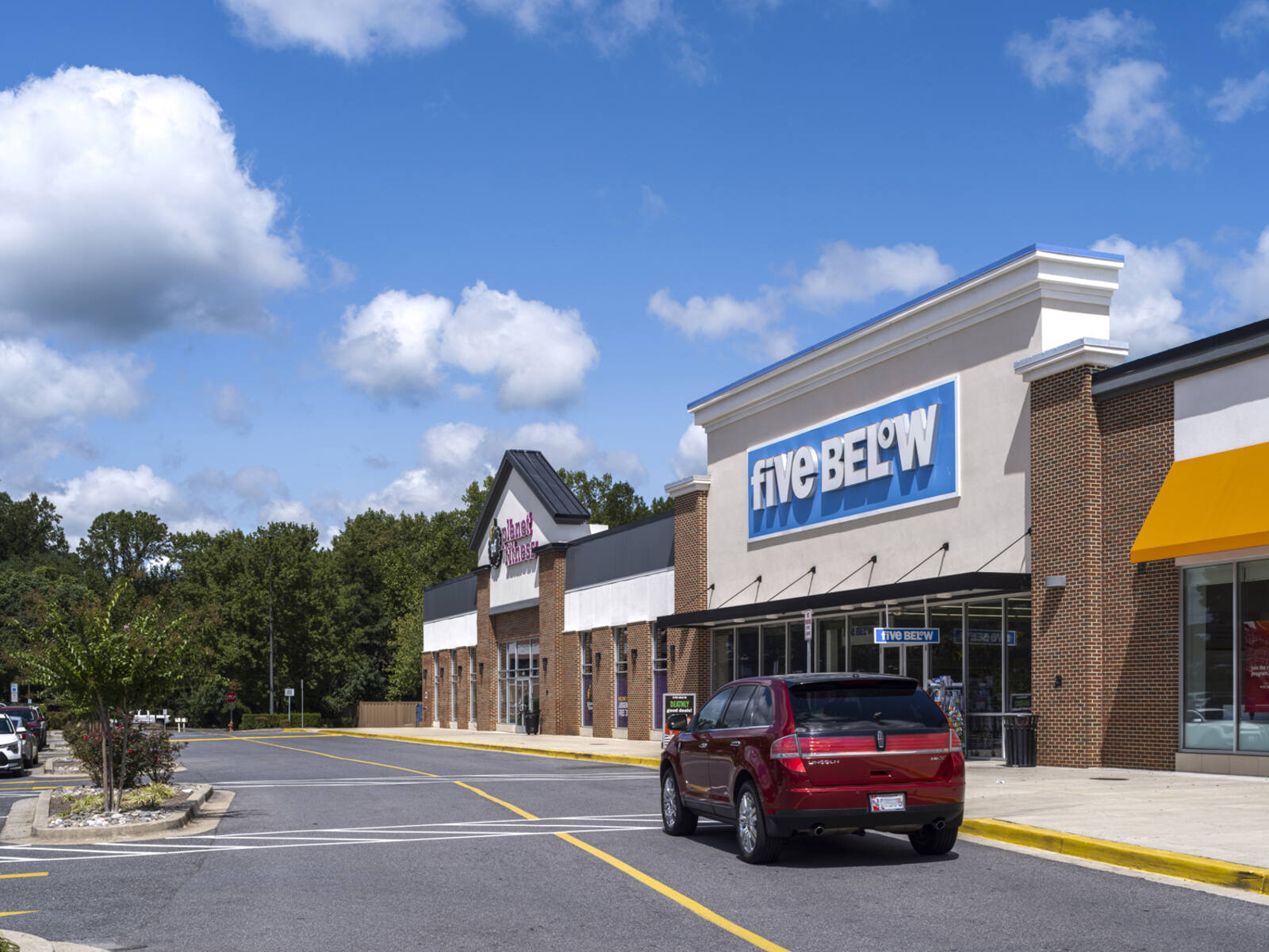 Red SUV on access road in front of Five Below at Fox Run shopping center.