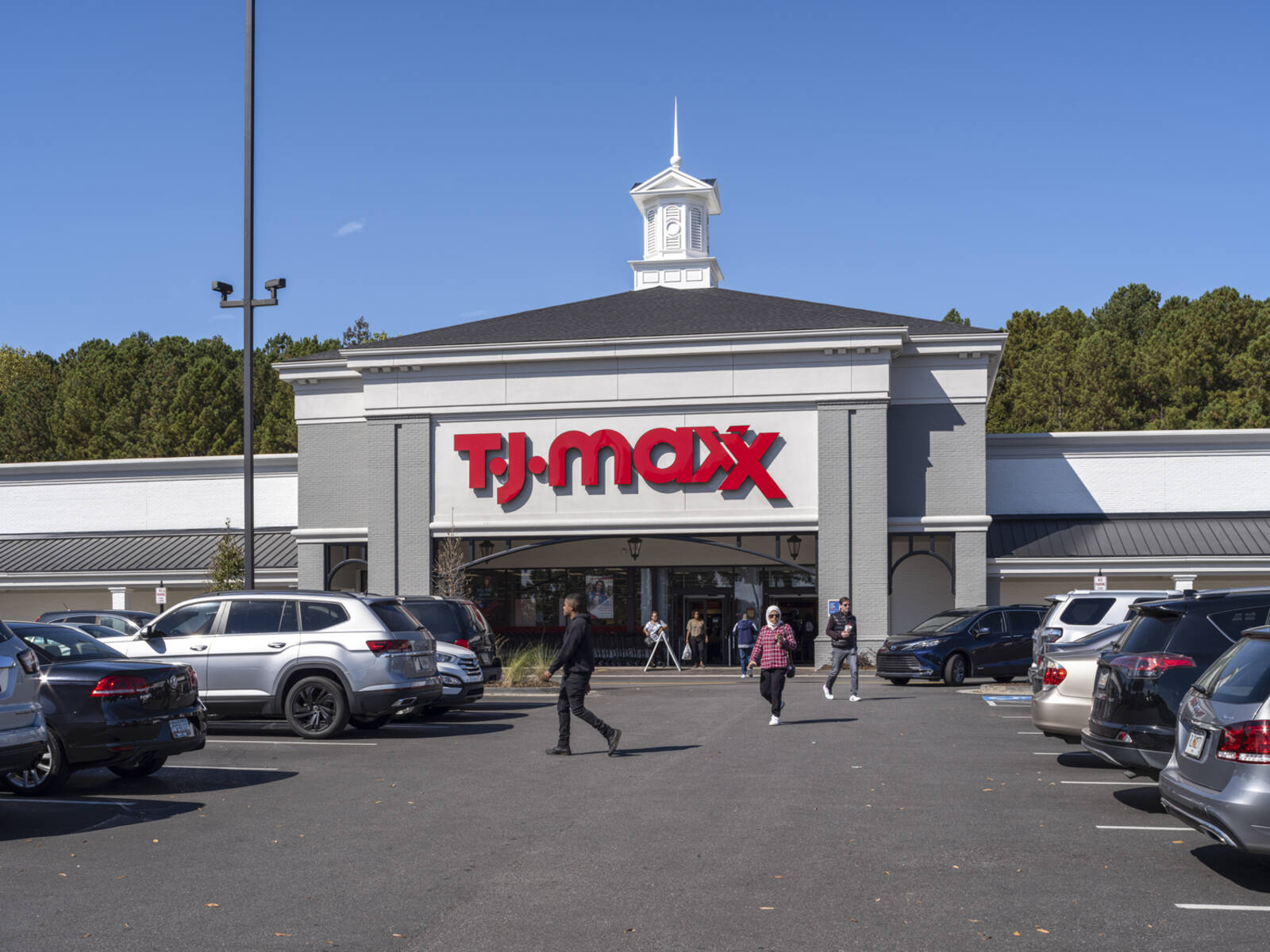 Customers approach their cars in the parking lot of TJ Maxx.