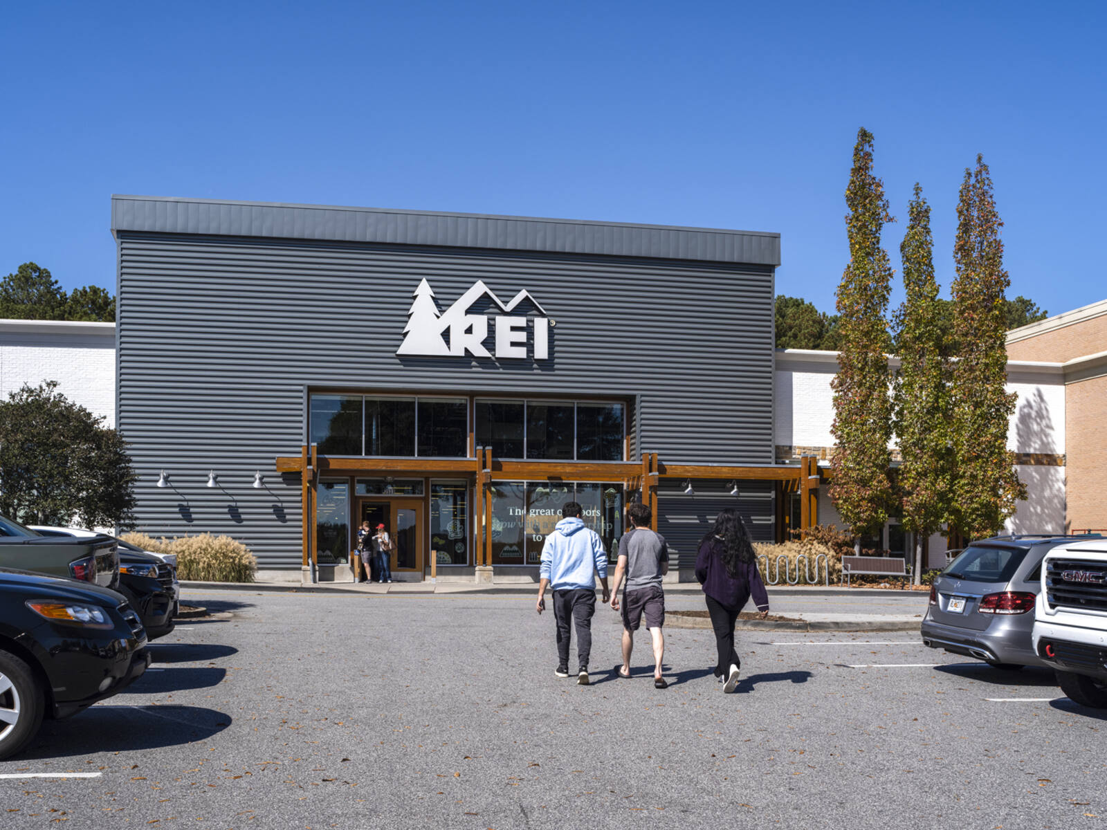 Pedestrians approach REI through parking lot.
