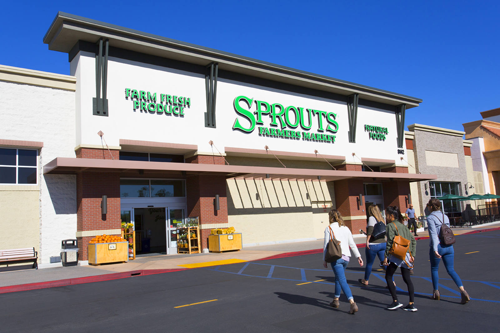 Four people walking towards the entrance of Sprouts Farmers Market