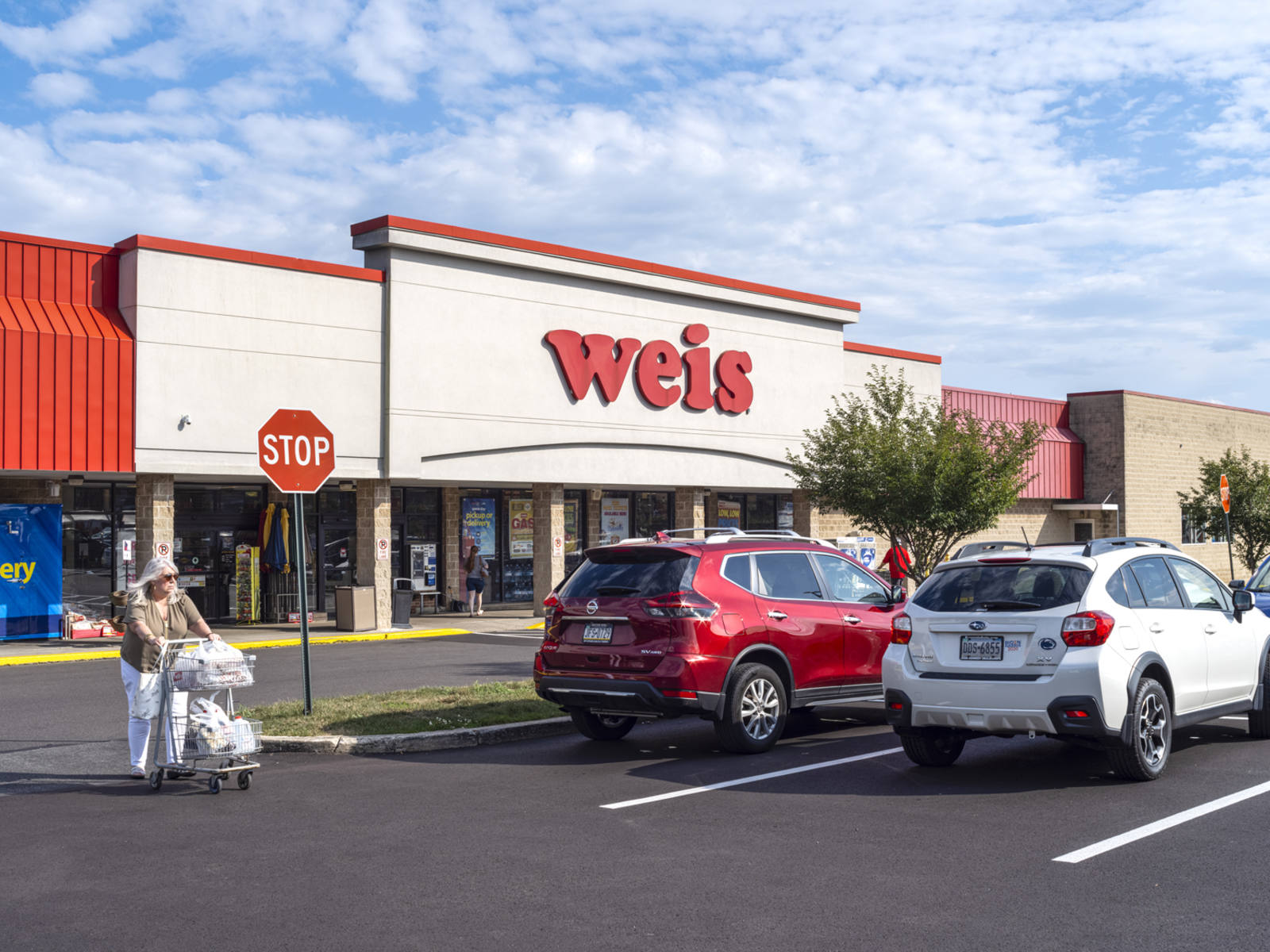 Woman with cart in parking lot of Weis supermarket.