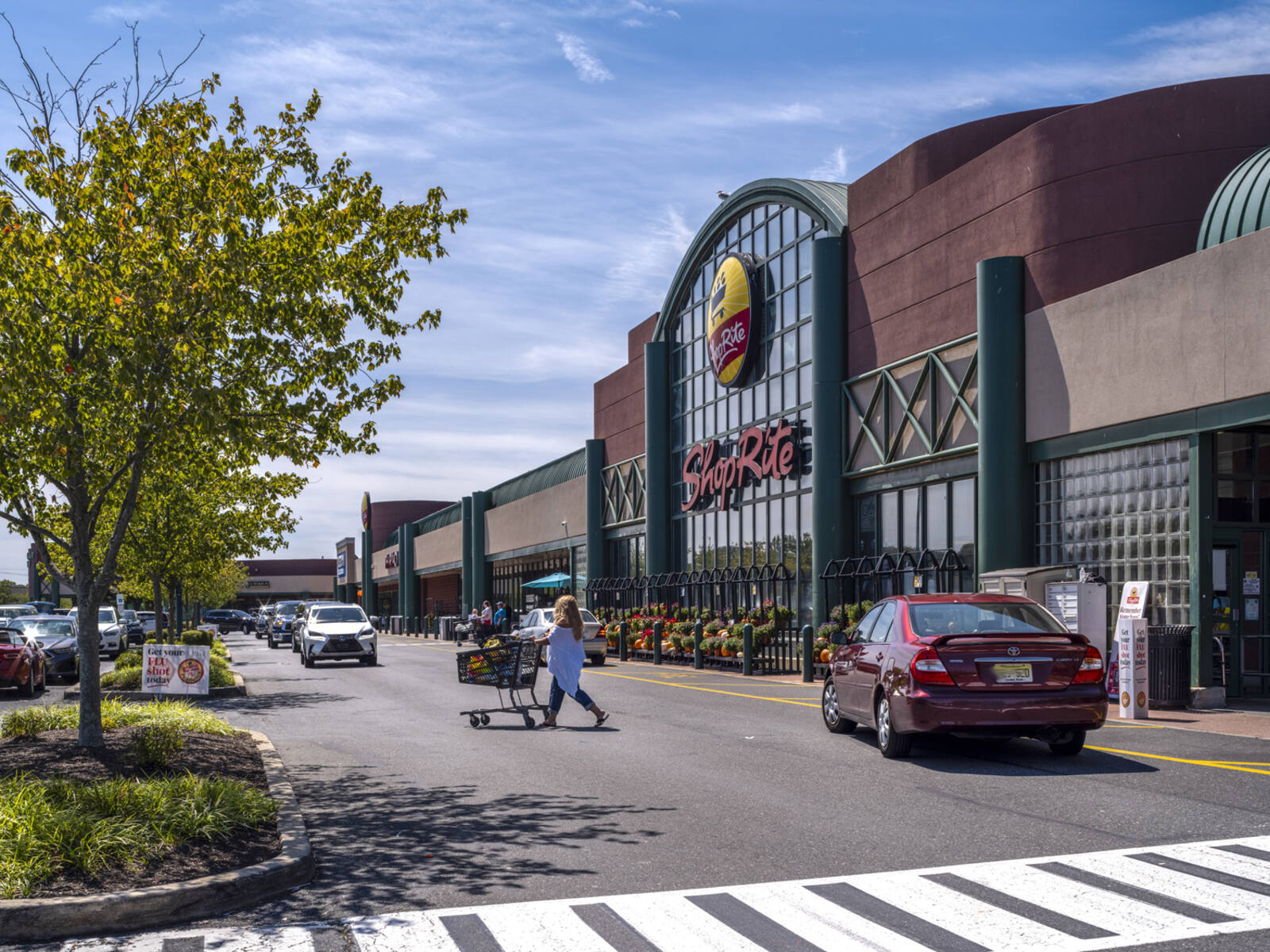 Red car and customer with car in crosswalk for ShopRite.