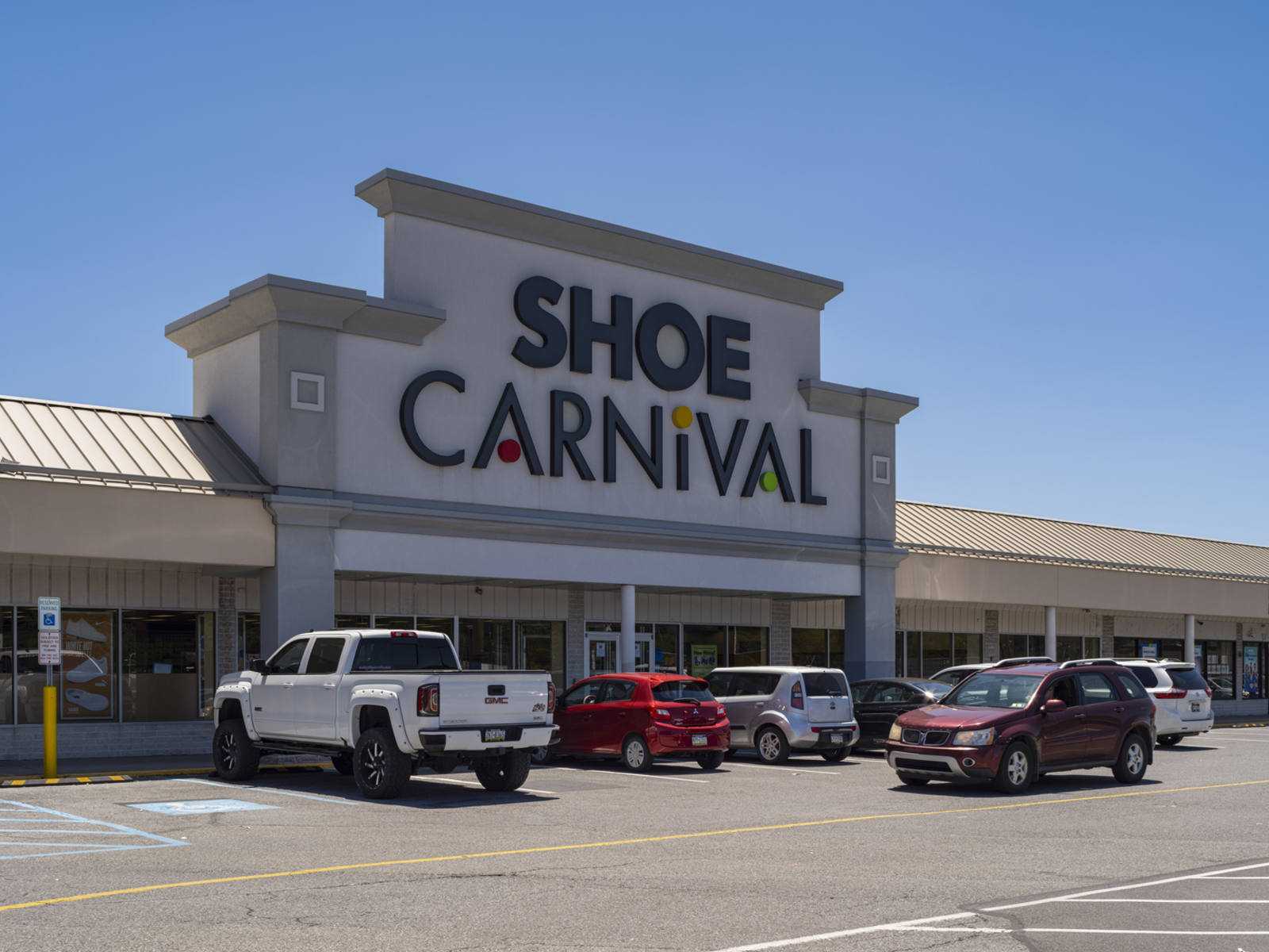 White pick up truck and other cars parked along entrance of Shoe Carnival