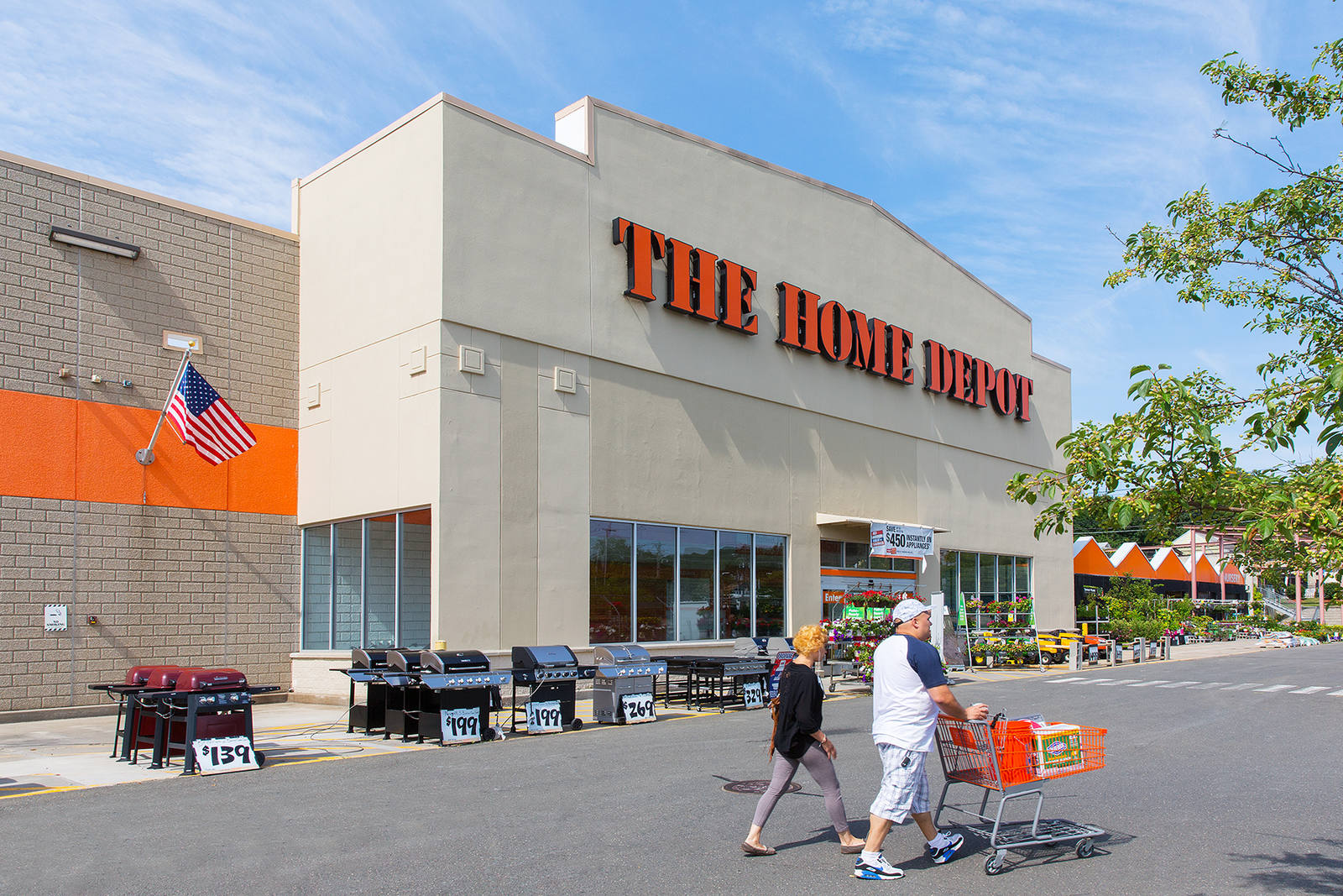 Two people with shopping cart walking outside entrance of The Home Depot