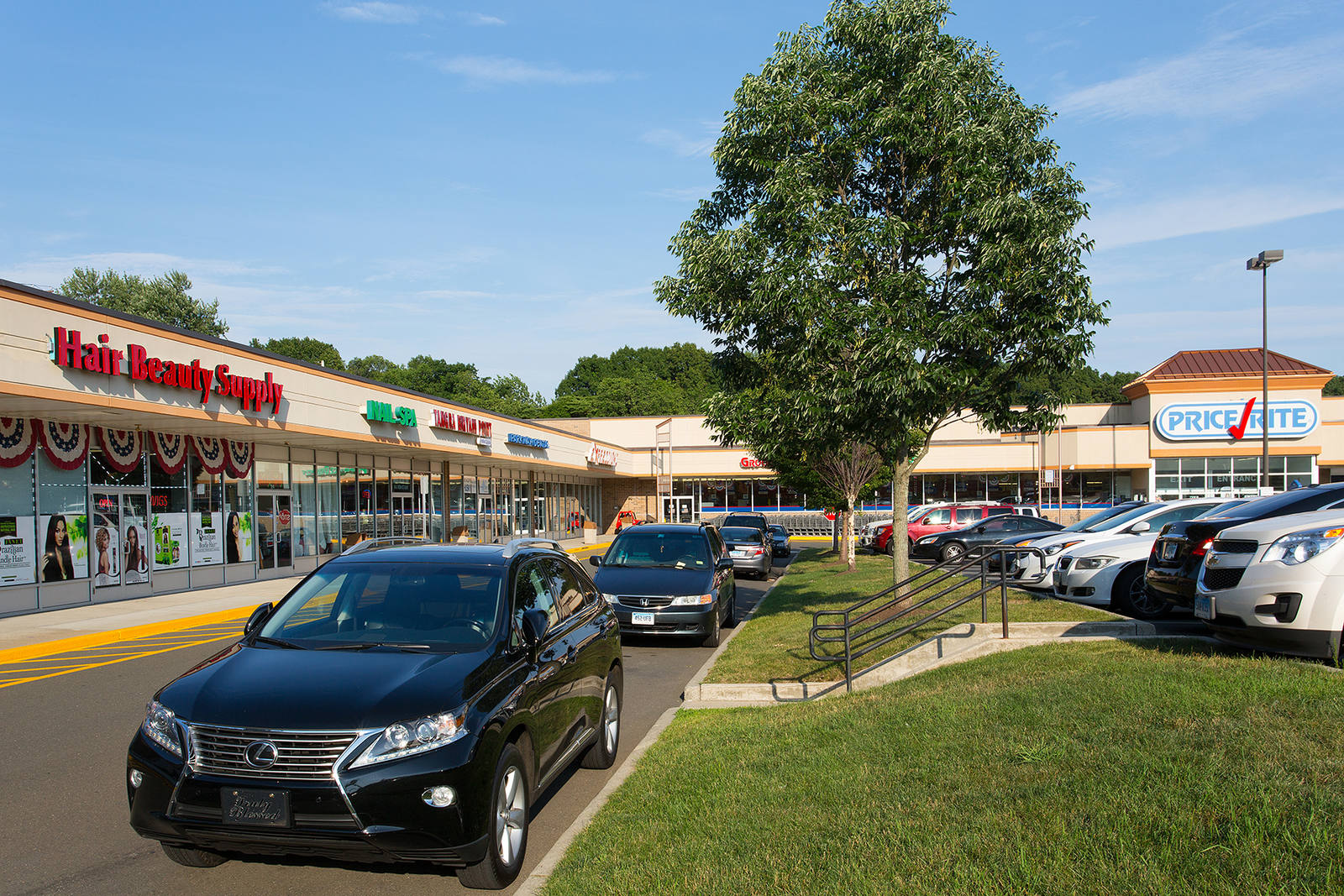 Black car parked by tree along small shops in Hamden, Connecticut