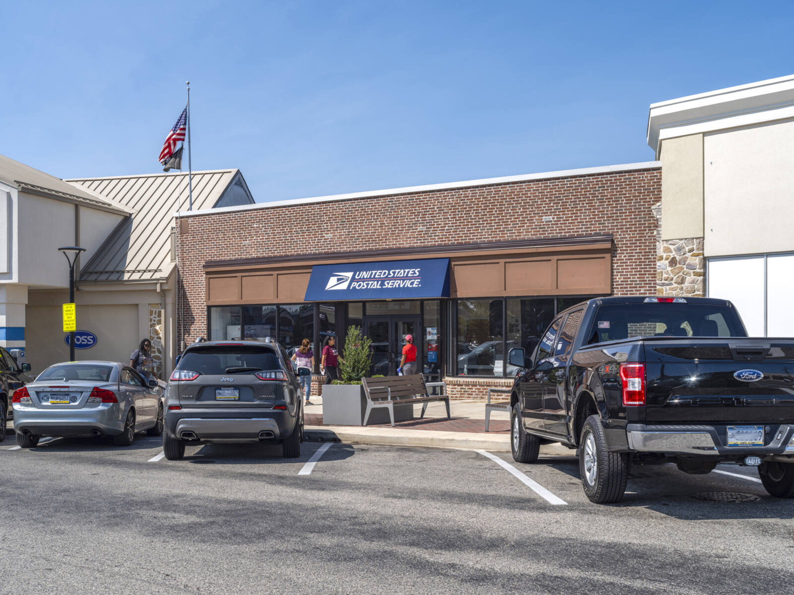 USPS with truck and cars in front parking lot.