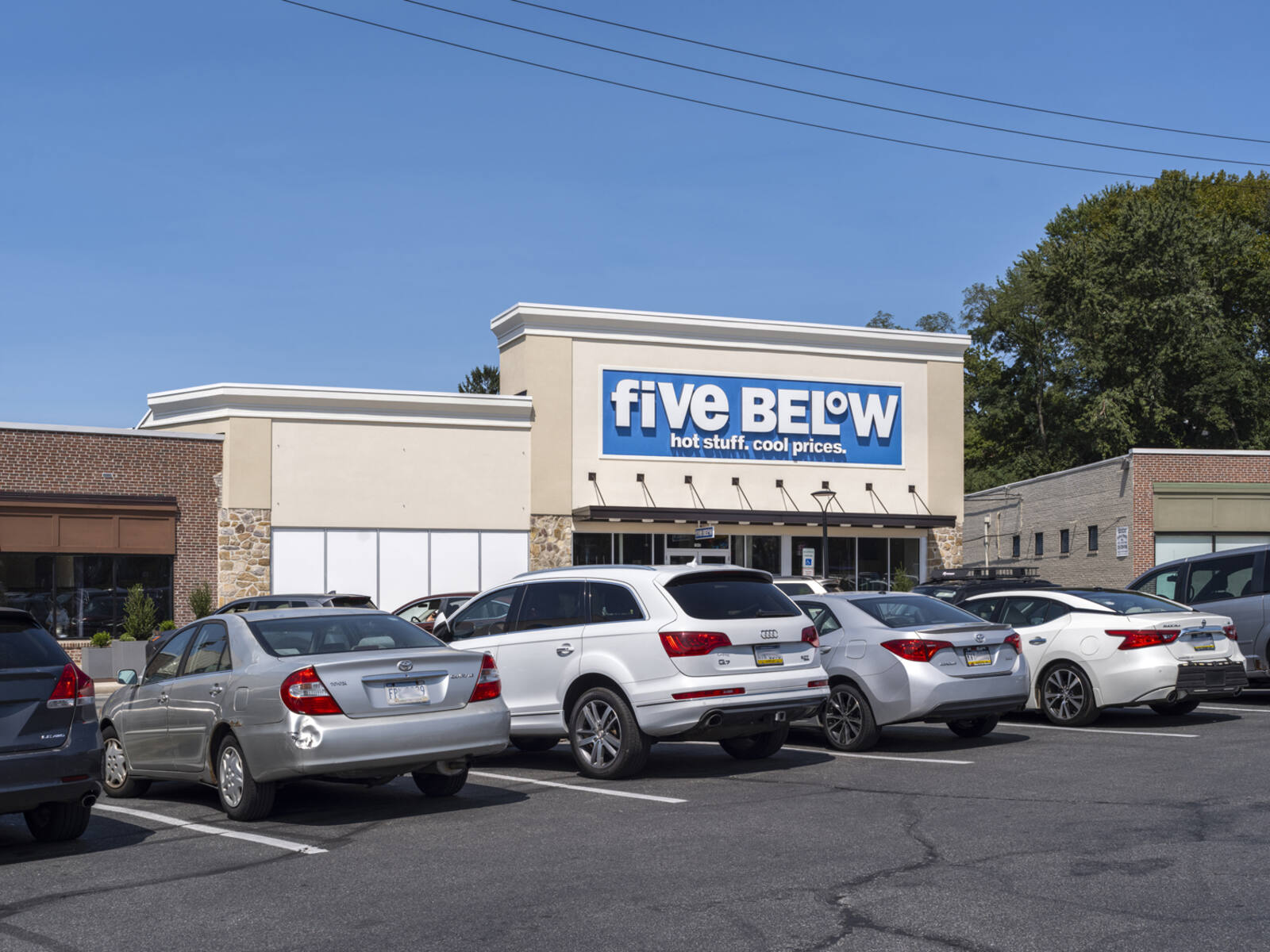 Line of cars at parking lot in front of Five Below store.