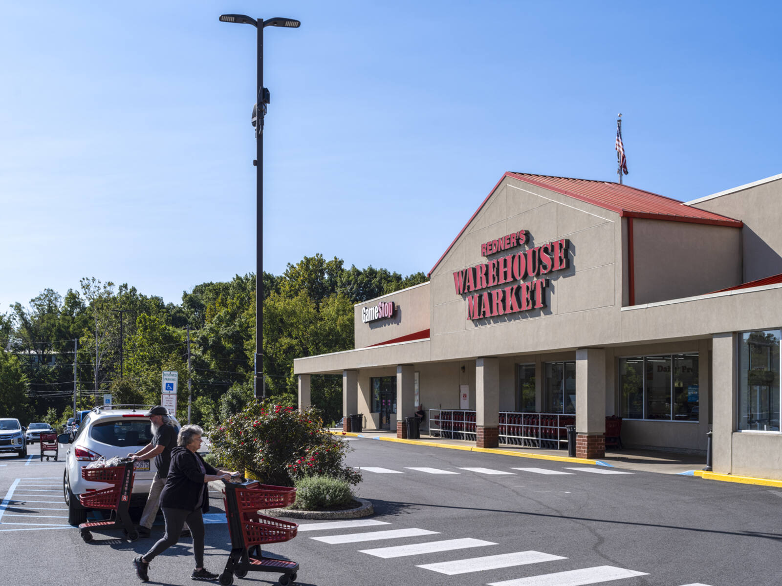 Redner's Warehouse Market parking lot with 2 patrons pushing carts in foreground.