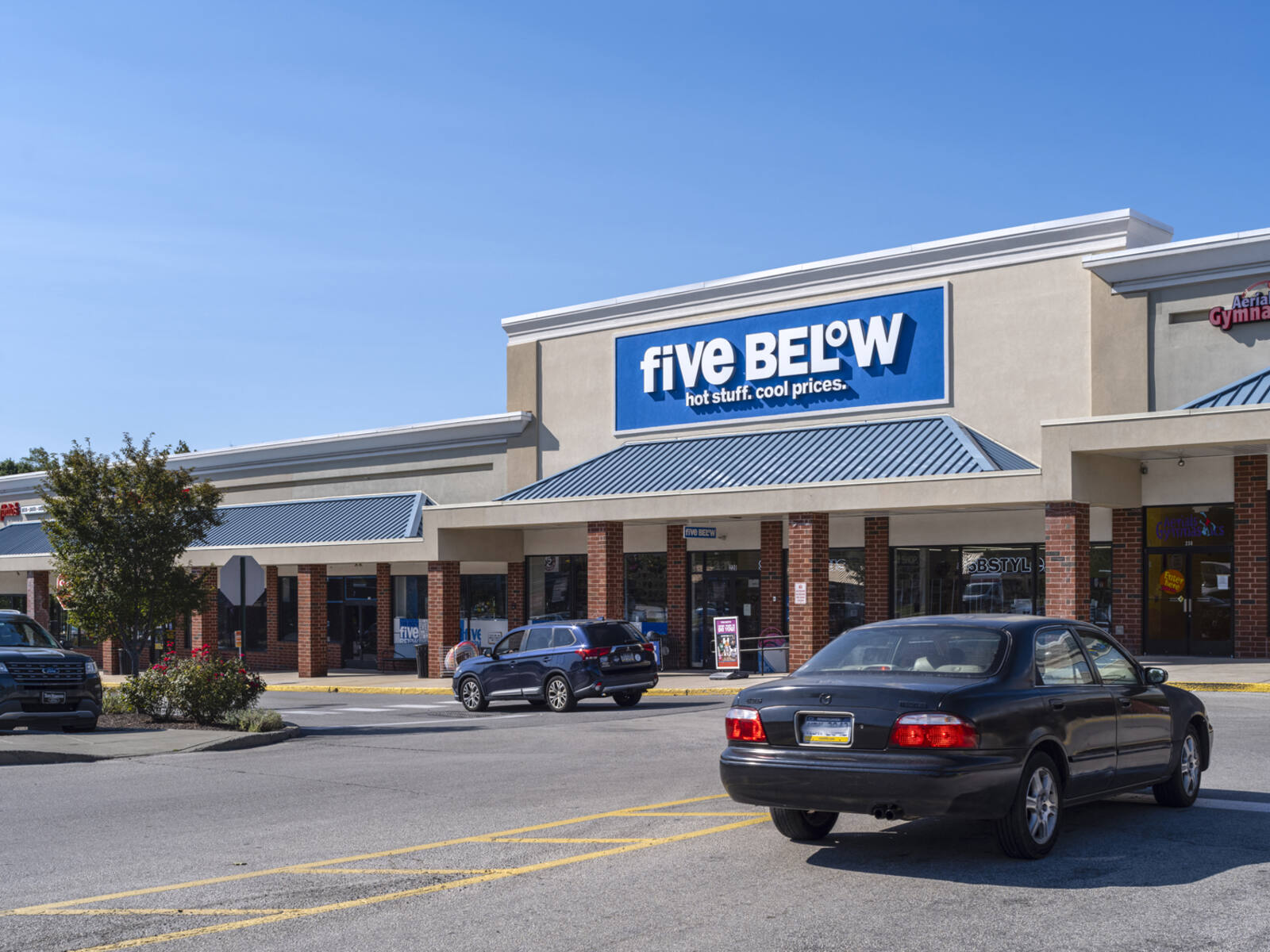 Cars turning on access road in front of Five Below store.