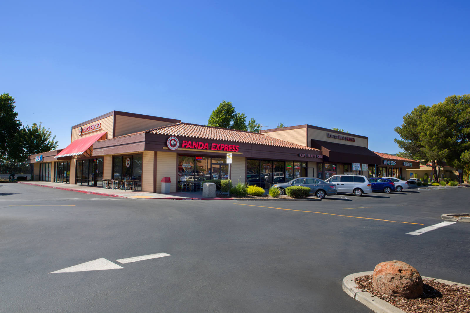 Corner entrance of Panda Express with cars parked on the right side
