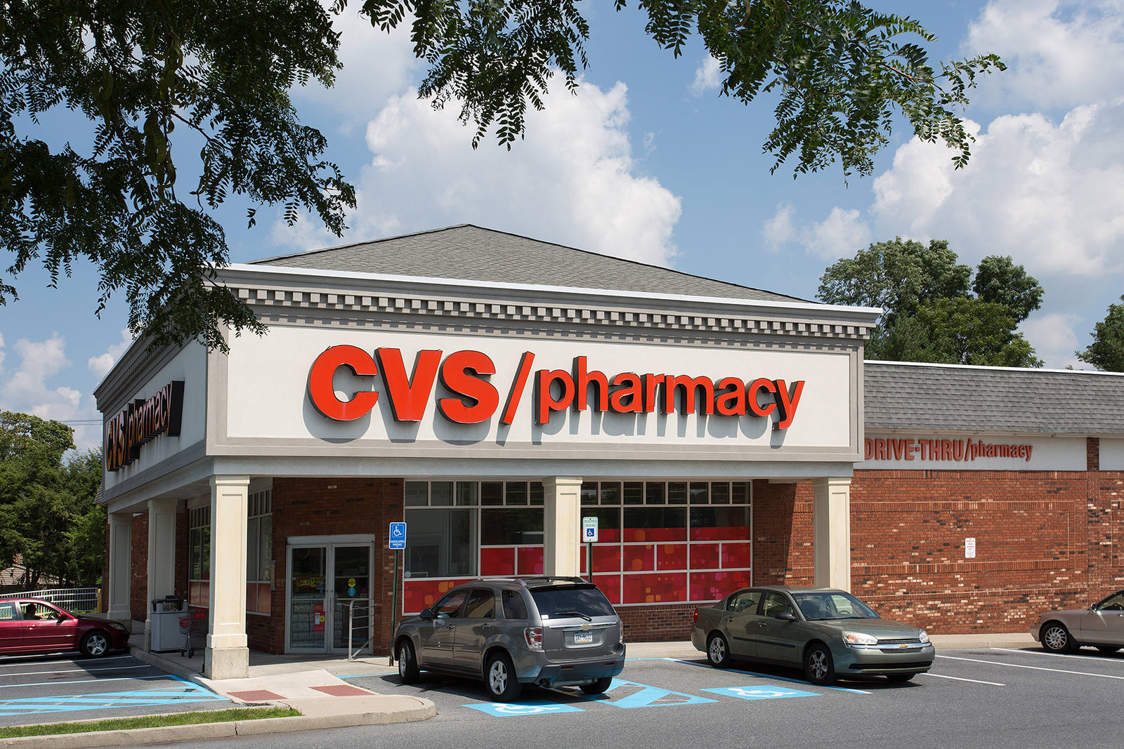 Tree overhanging the entrance of CVS with two cars parked in front