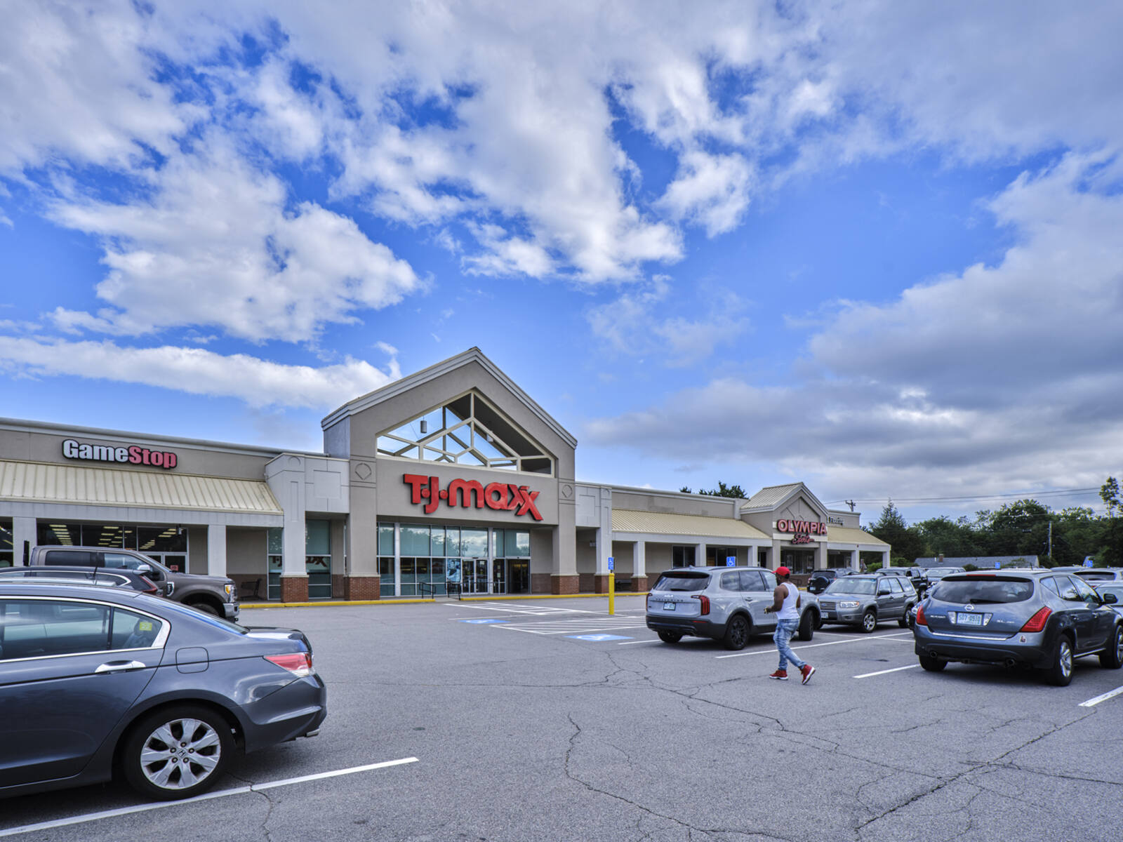 Clouds and blue sky over TJ Maxx as pedestrian approaches store.