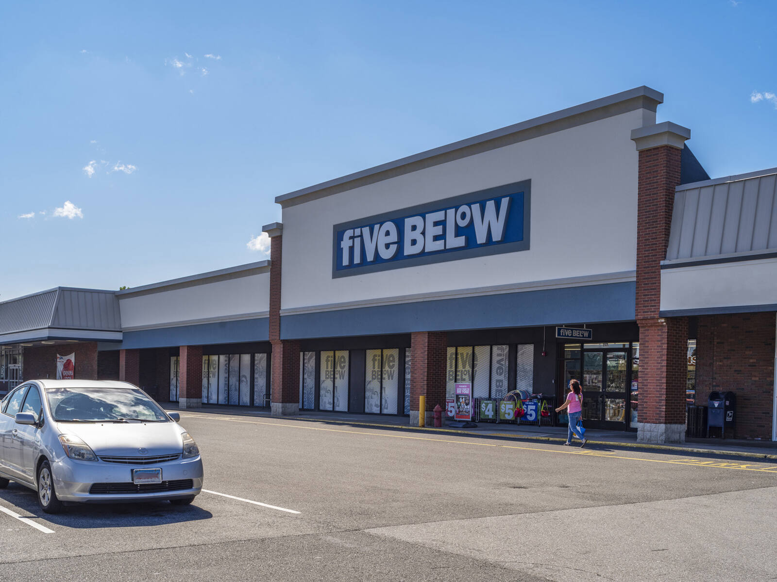 Parking lot with grey car in front of Five Below.