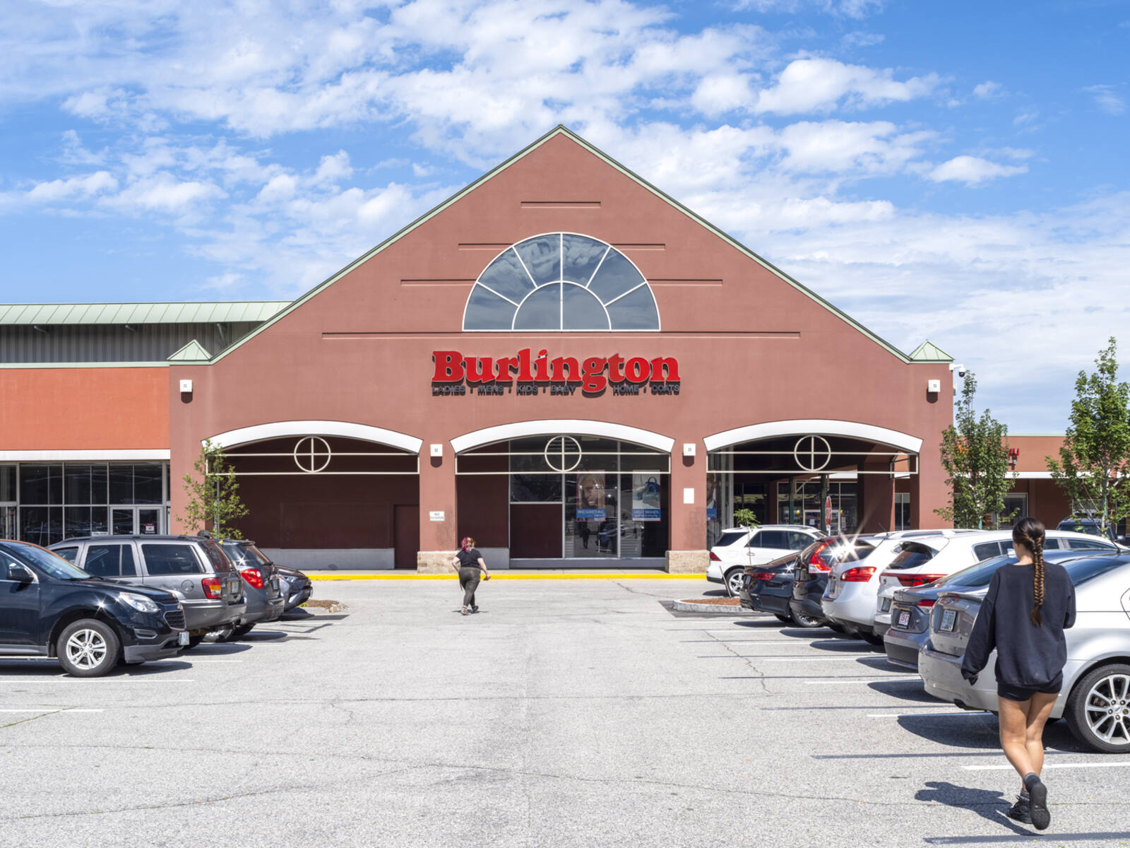 Woman walking past cars in parking lot at Burlington.