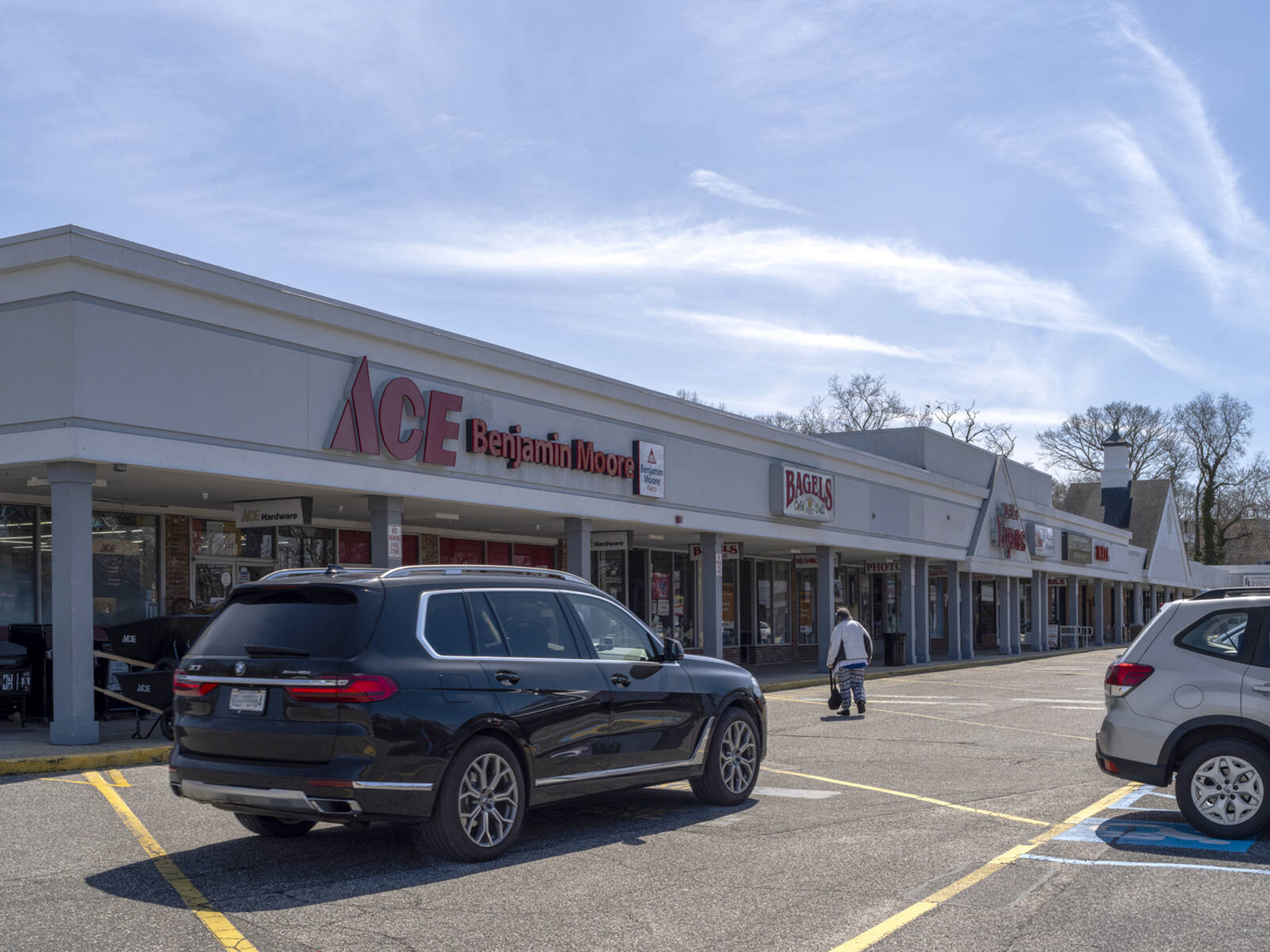 Dark SUV passes ACE Benjamin Moore store on access road at shopping center.