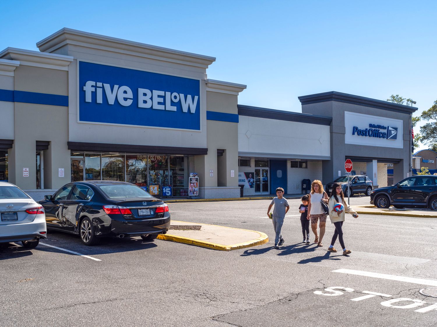 Family leaving Five Below store to a parking lot.