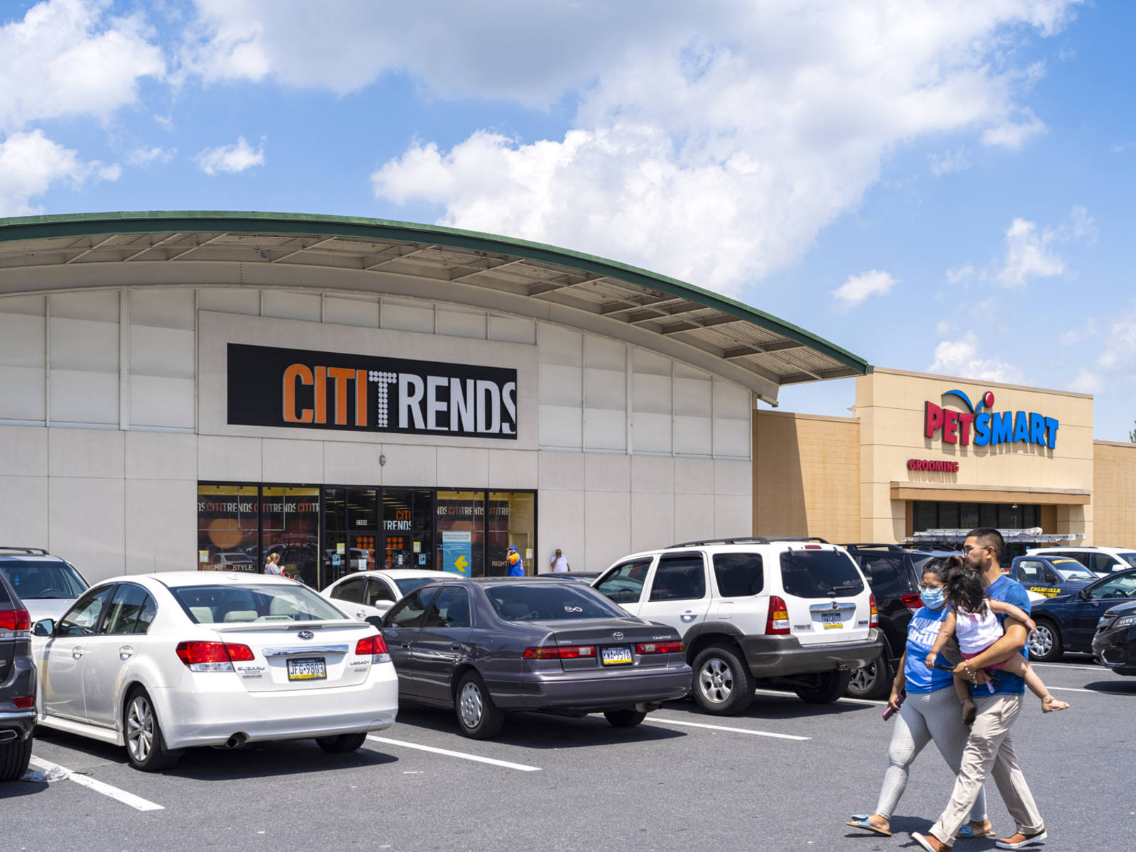 Parents holding child while passing CitiTrends, PetSmart at Lehigh Shopping Center.