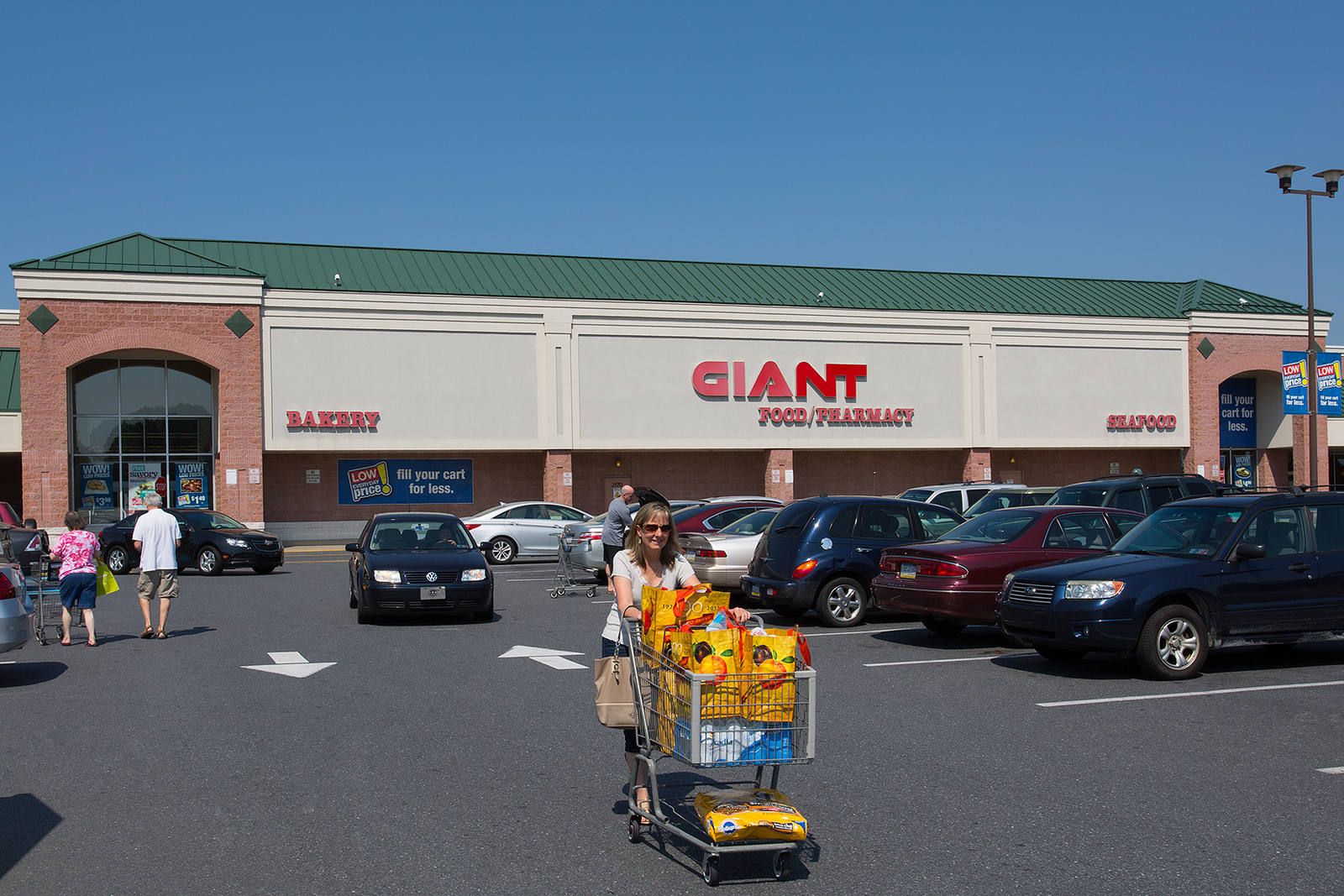 Customer with loaded shopping cart exiting Giant supermarket at Lehigh Shopping Center.