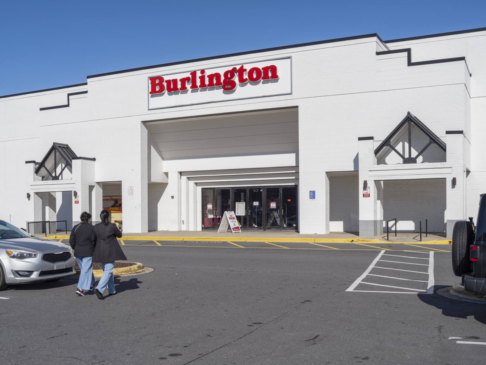 Two patrons approach Burlington store from parking lot.