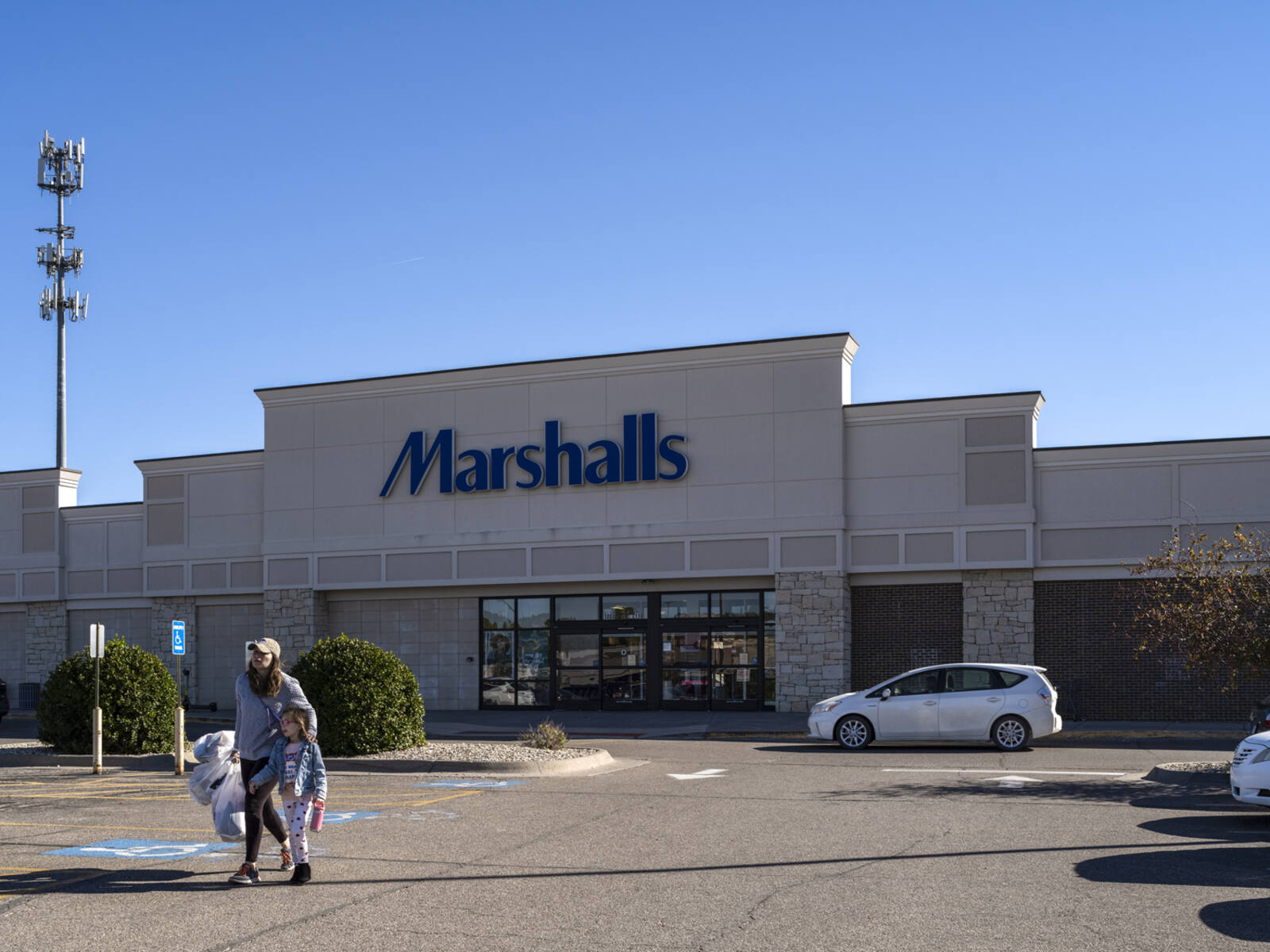 Woman with child exiting Marshalls with white bags.