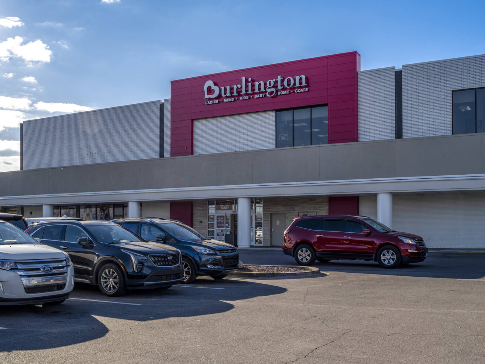 Burlington store with row of SUVs parked in front.
