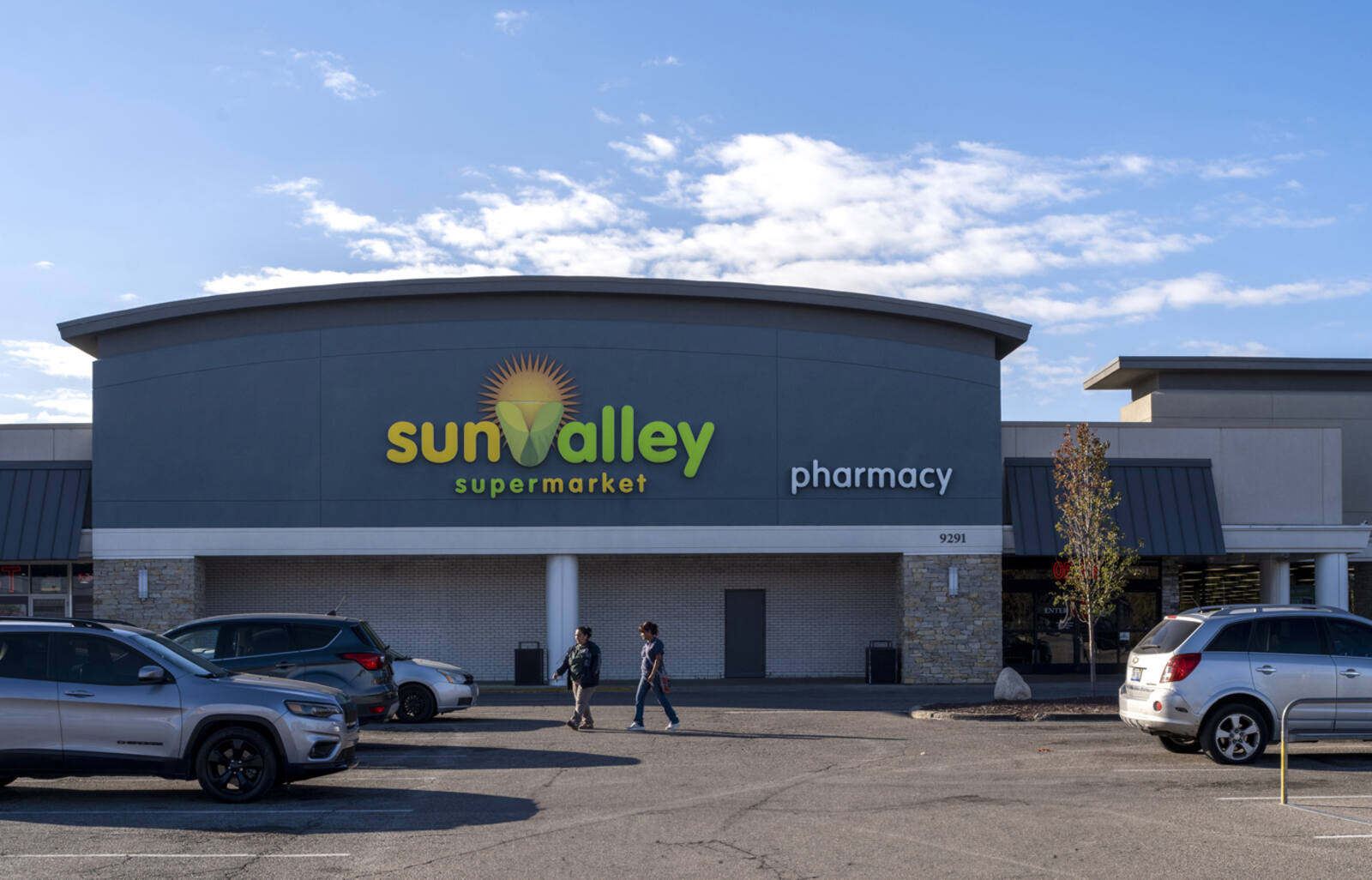 Two patrons entering Sun Valley Supermarket from parking lot.