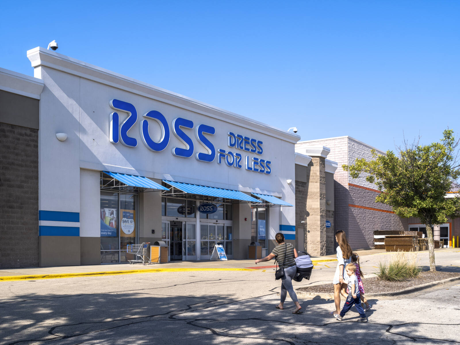 Couple with a child walk toward Ross Dress for Less past a planter.