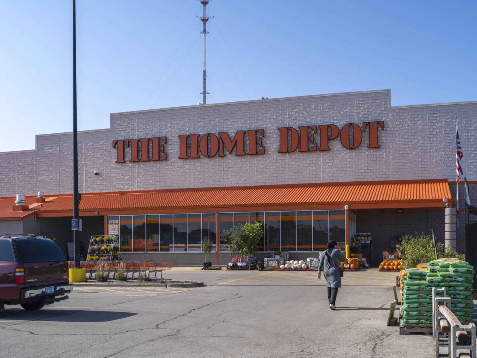 Home Depot entrance with woman and truck in parking lot.