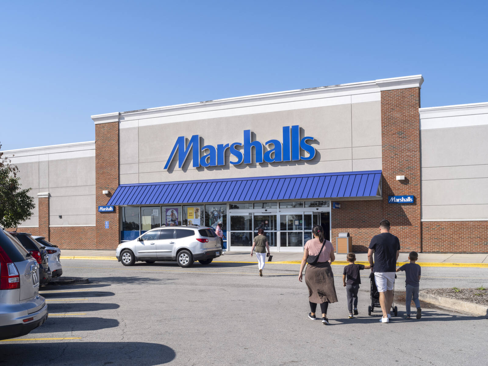 Family walking through parking lot approaching Marshalls store.