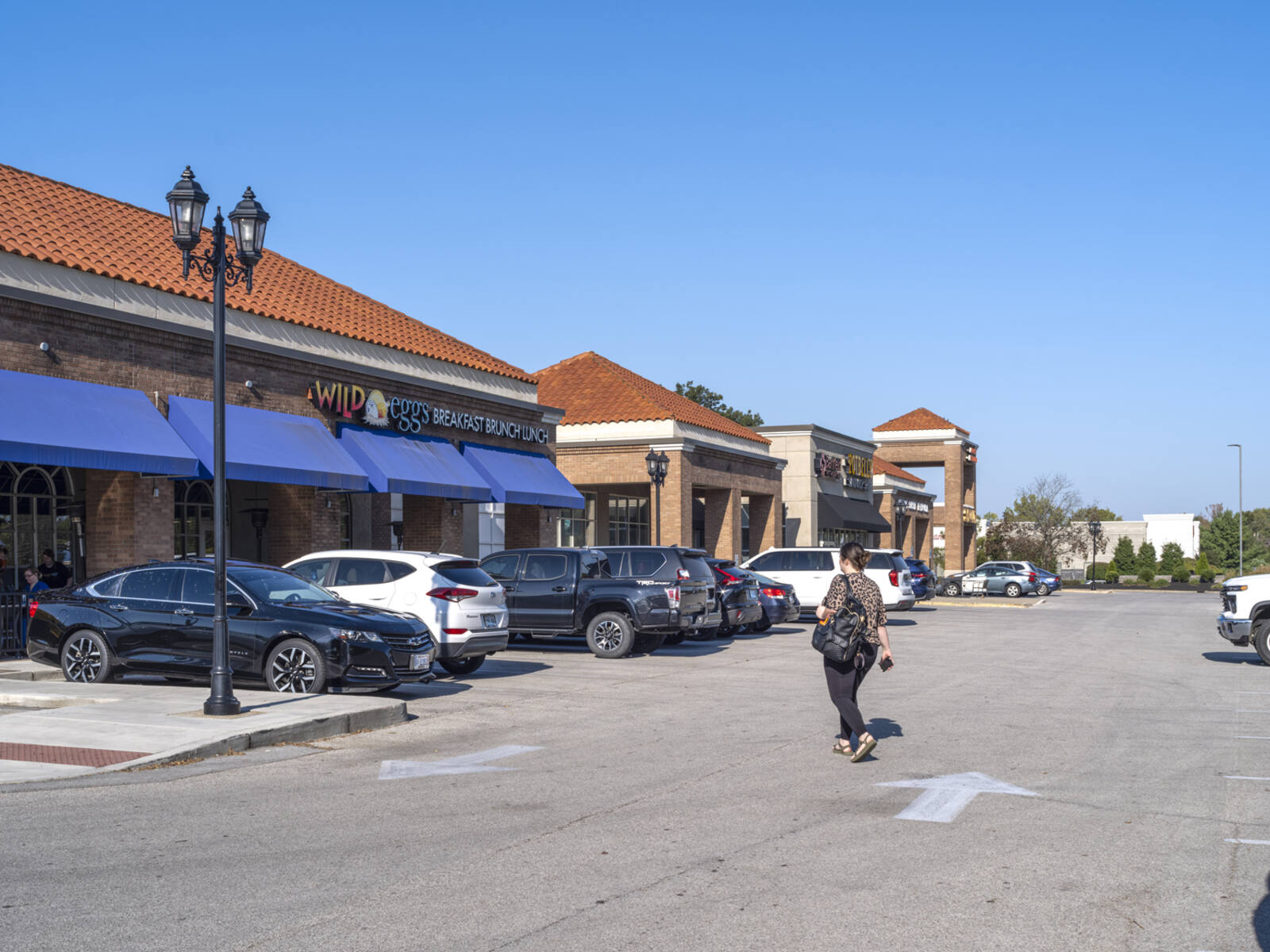 Woman approaches Wild Eggs restaurant via access road in parking lot.