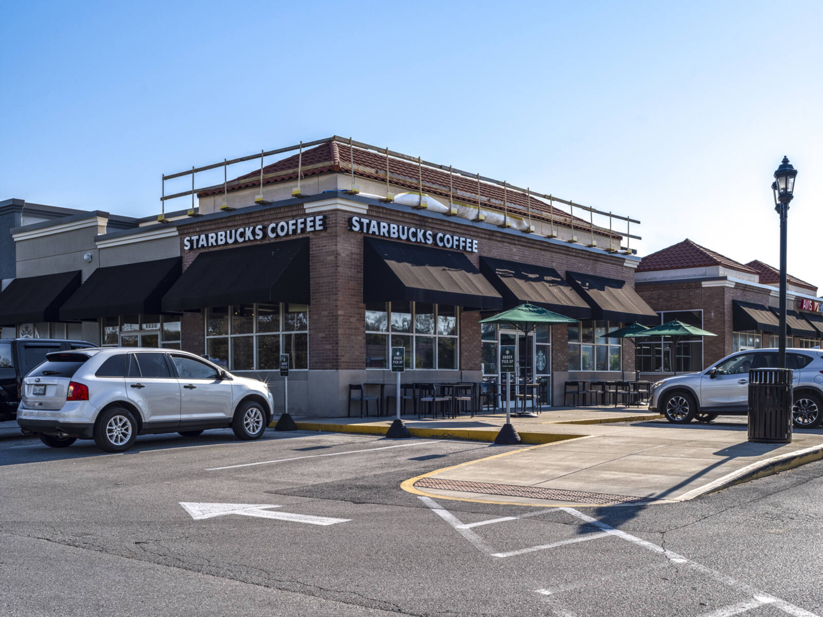 Busy lot at Starbucks Coffee with outdoor seating cover in green umbrellas.