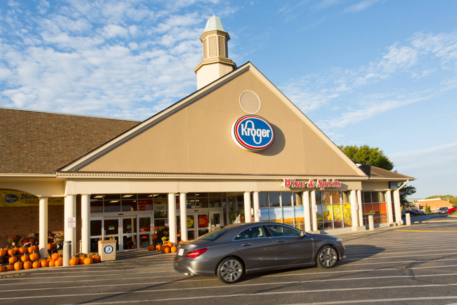Dark grey car in front of entrance of Kroger with pumpkin display outside