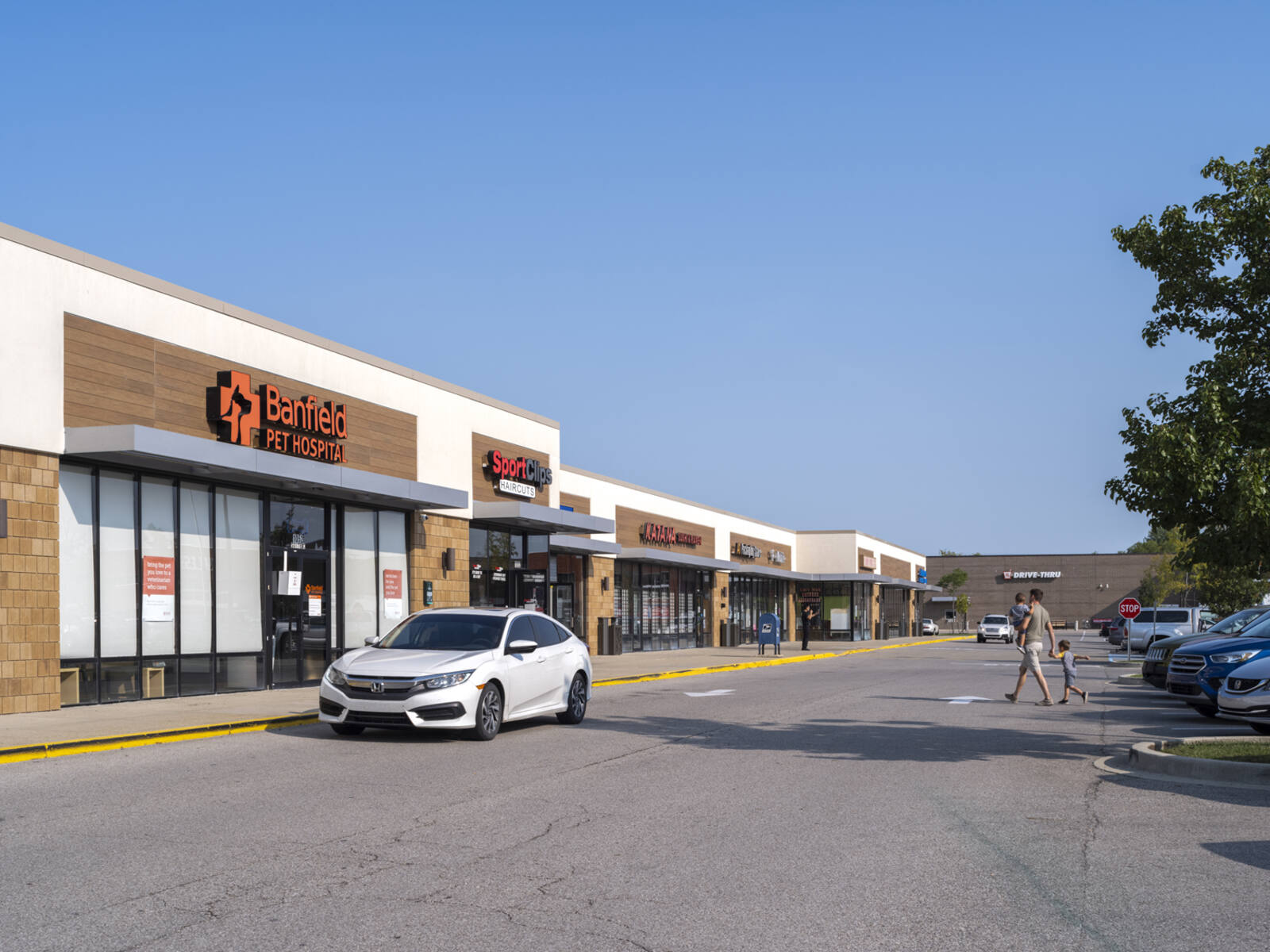 Man with two children in crosswalk approaching Banfield Pet Hospital.