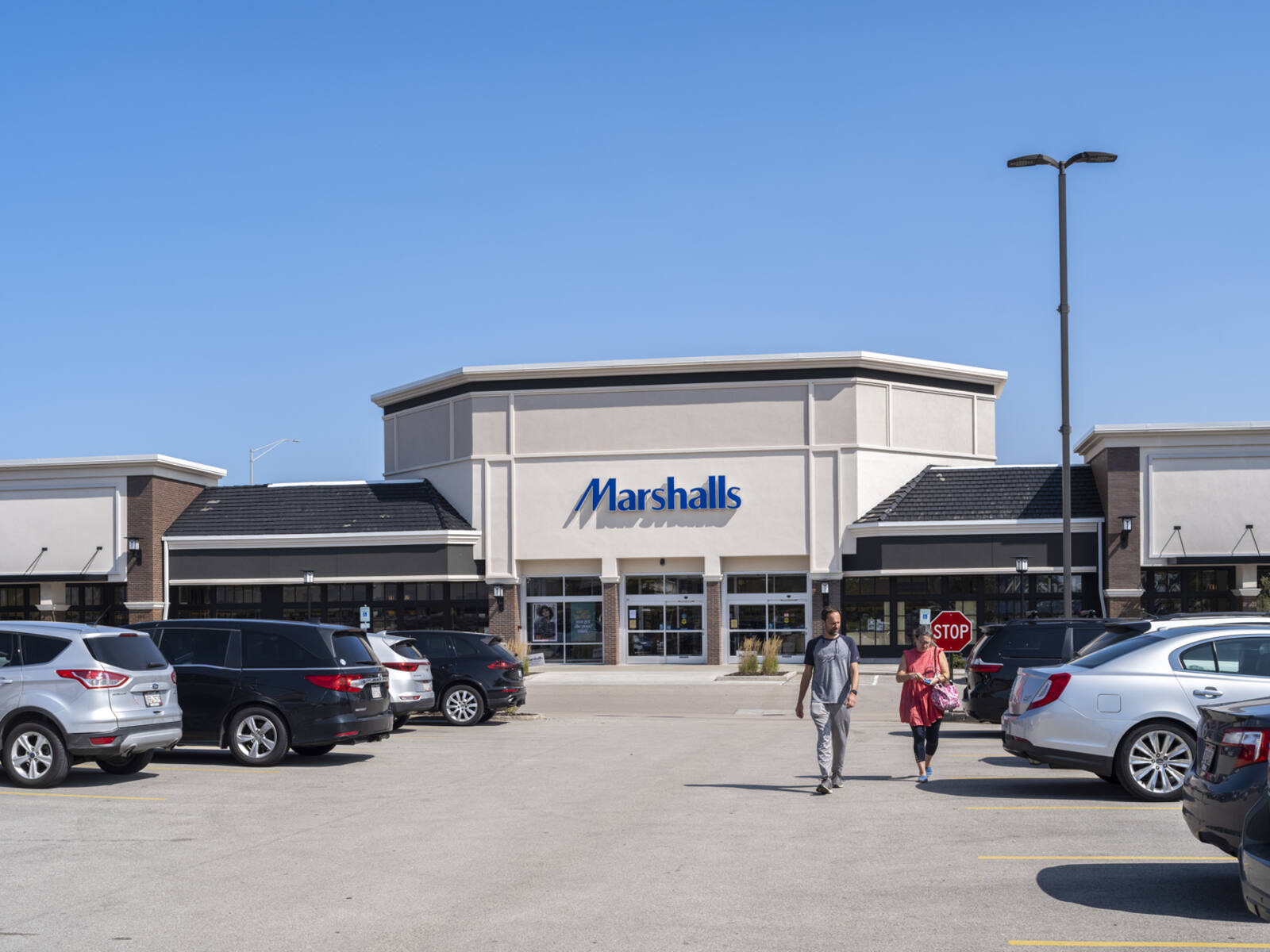 Two customers leaving Marshalls into parking lot.