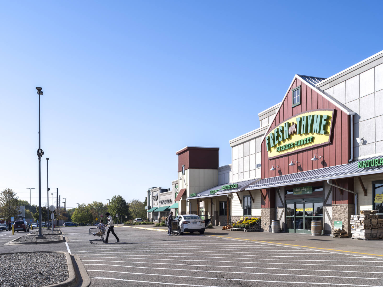 Man pushing cart with child leaving Fresh Thyme Farmer's Market.