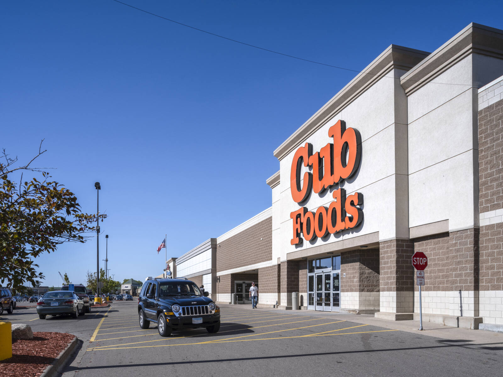 Black jeep passing Cub Foods on access road at entrance.