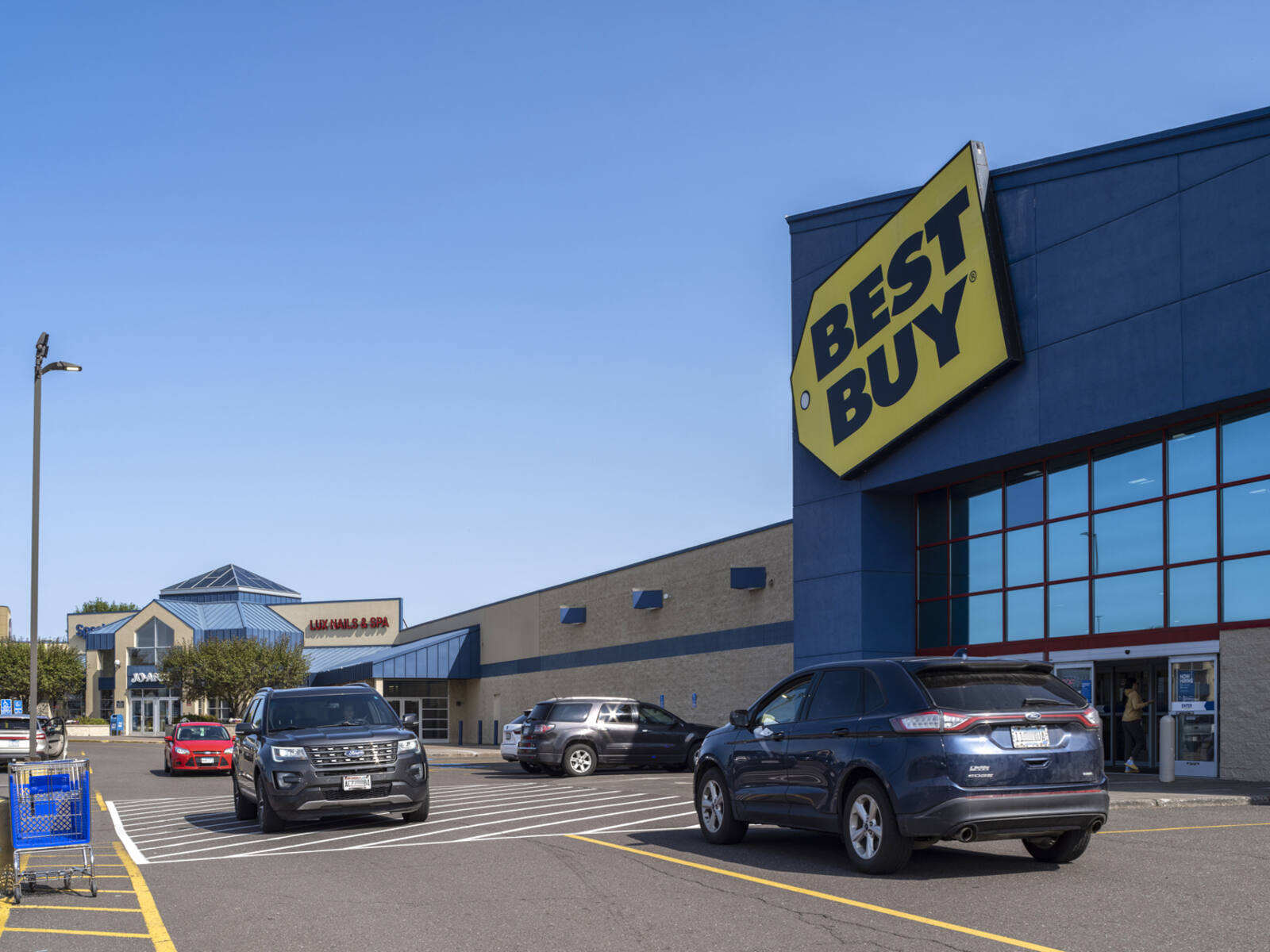 Grey cars passing in front of Best Buy access road.