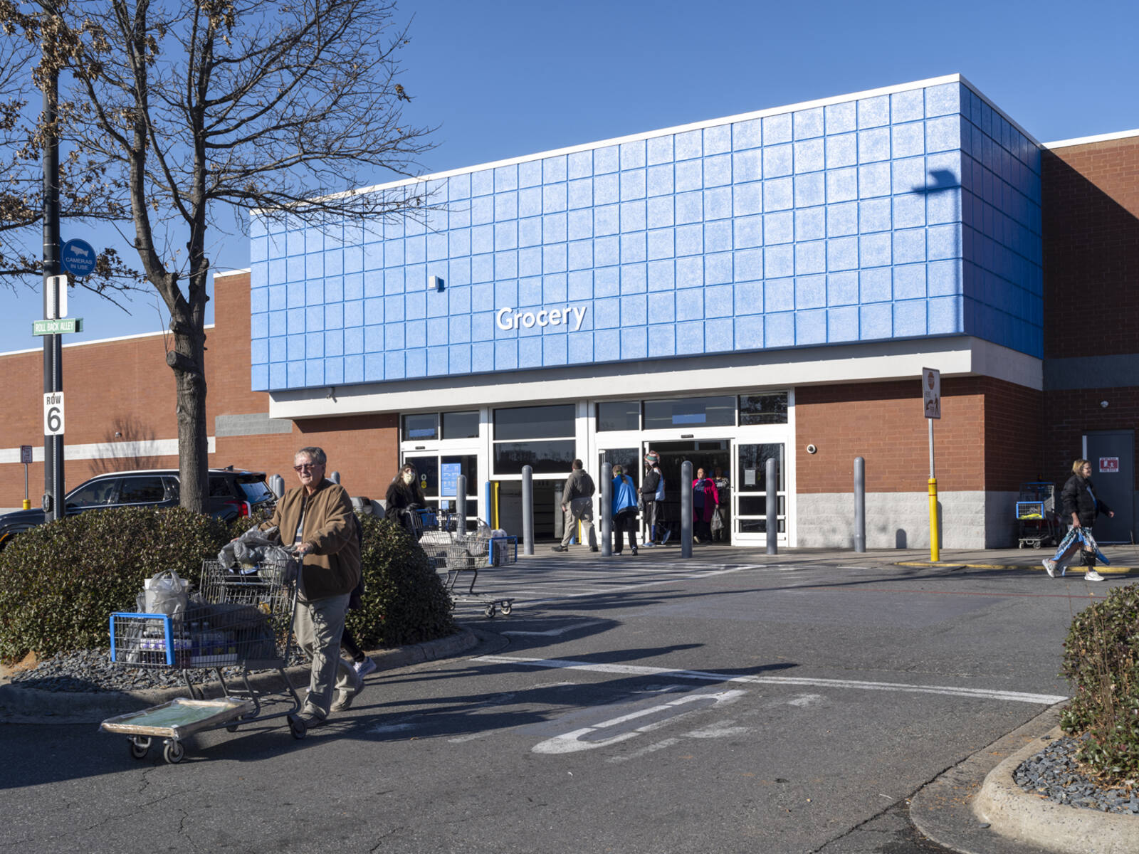 Patrons exiting Walmart onto parking lot access road.