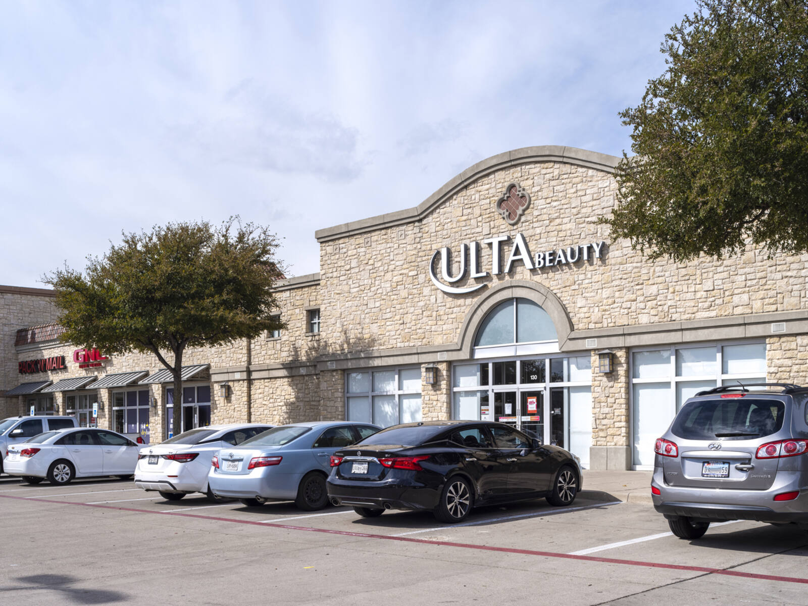 Two trees and cars in front of Ulta Beauty.