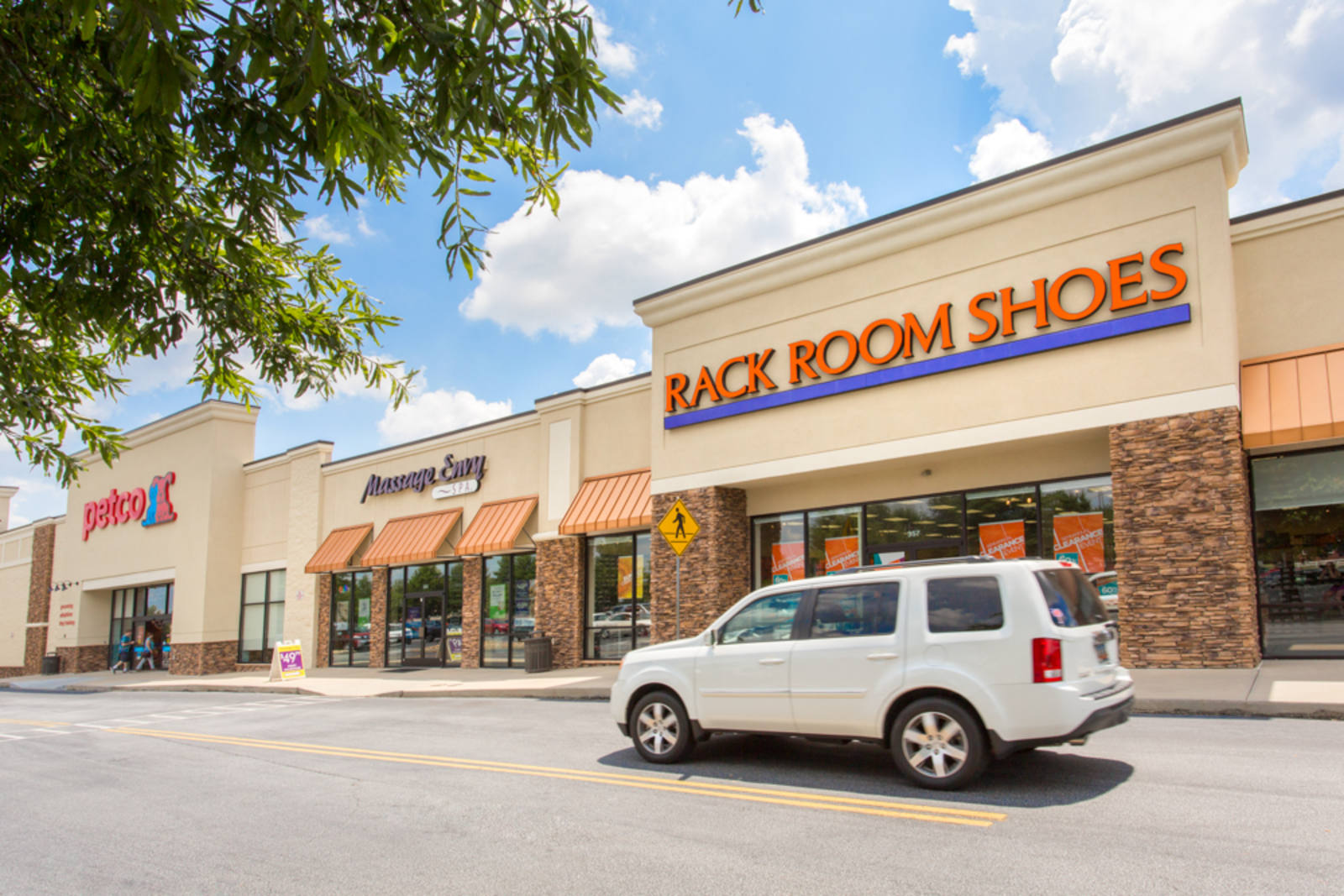 White SUV passing Rack Room Shoes store at Fairview Corners I & II.