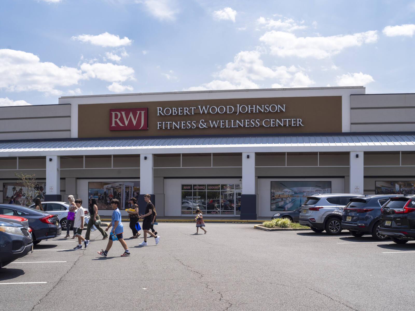 RWJ gym with group of people walking towards their car in parking lot.