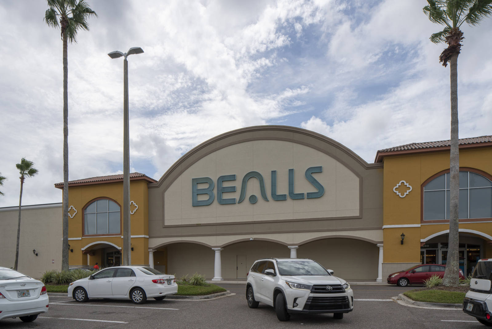 White cars and palm trees in the lot of Bealls store in St. Augustine, FL.