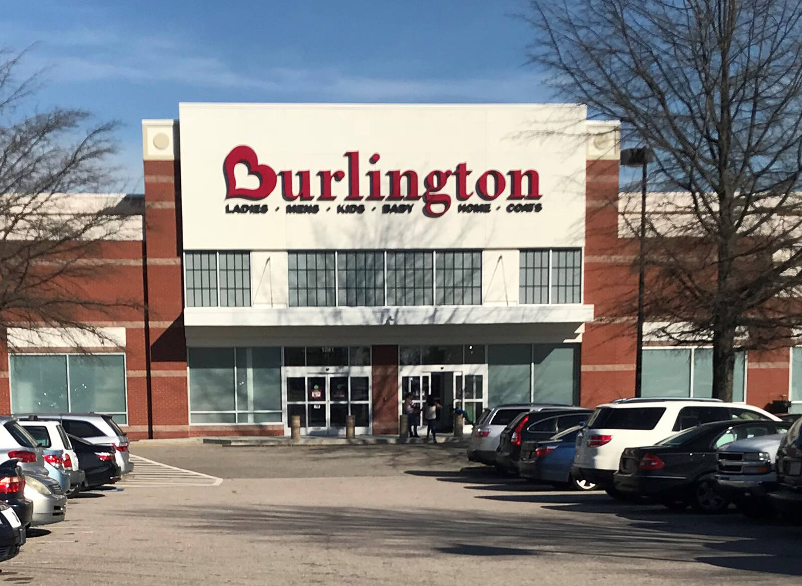 Parked cars on either side of entrance leading to Burlington with two bare trees on either side